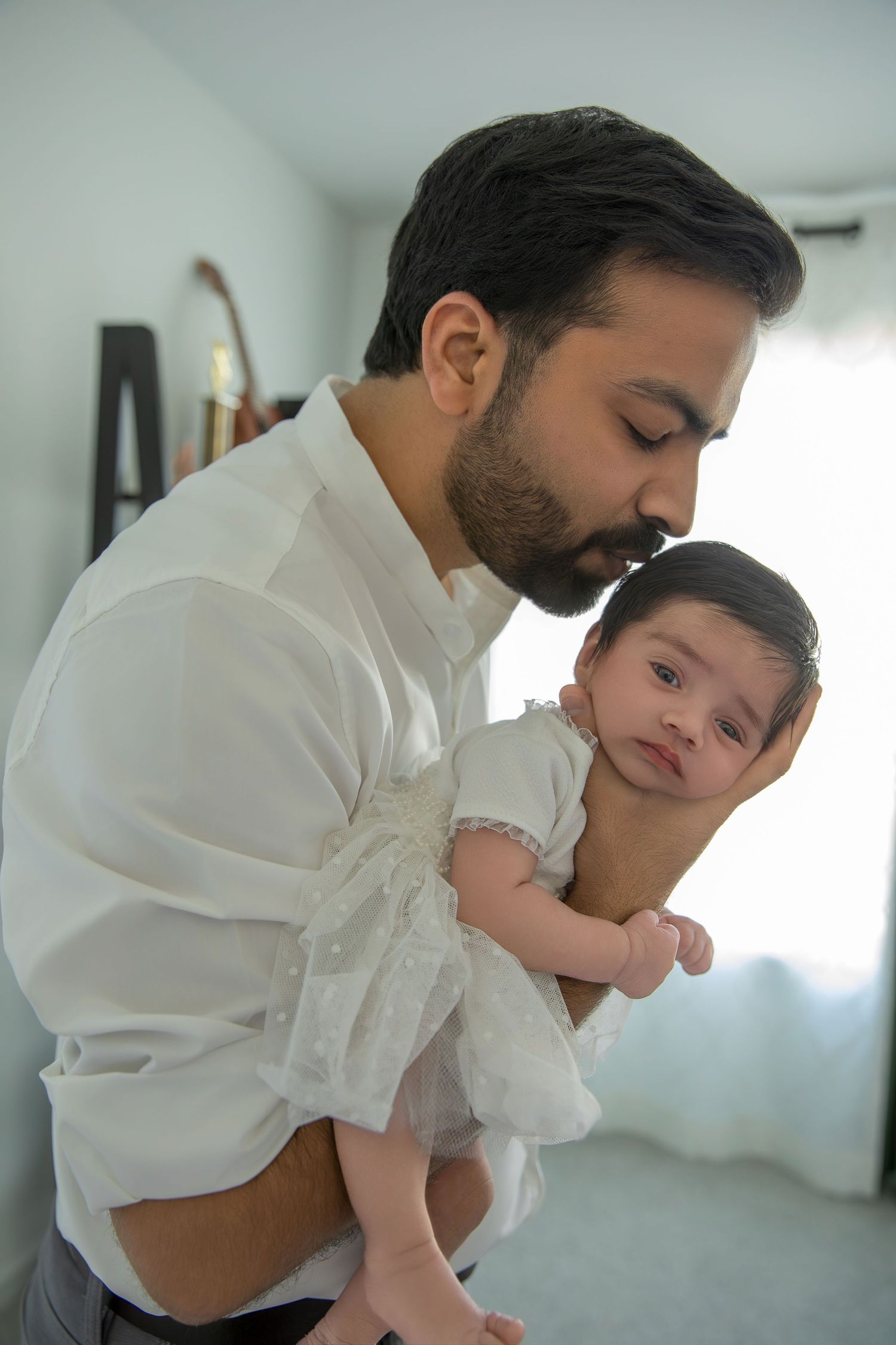 Parent in white shirt sharing affectionate moments with baby in white clothing.