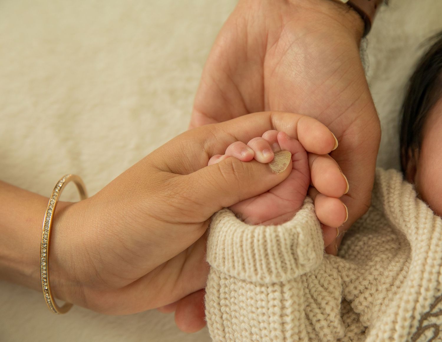 Close-up of tiny baby feet wrapped in cozy knitted fabric against a light background.