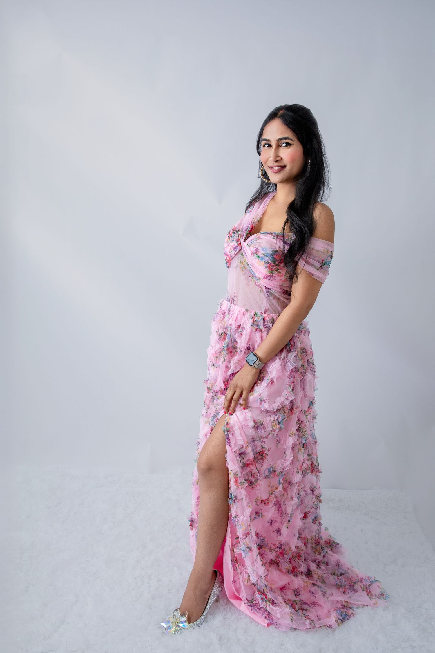 Elegant off-shoulder pink floral dress flows gracefully across a simple gray studio background.