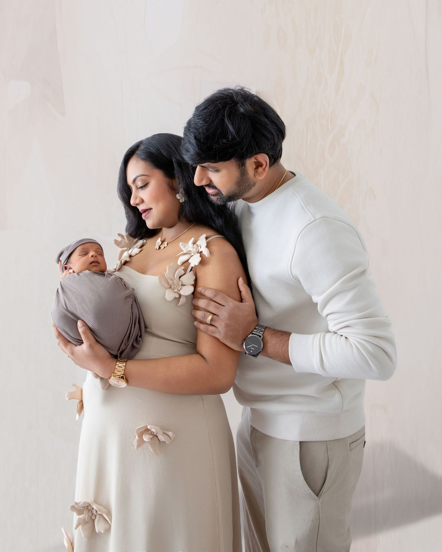 Couple in neutral tones embracing while expecting a baby in an intimate maternity photoshoot.