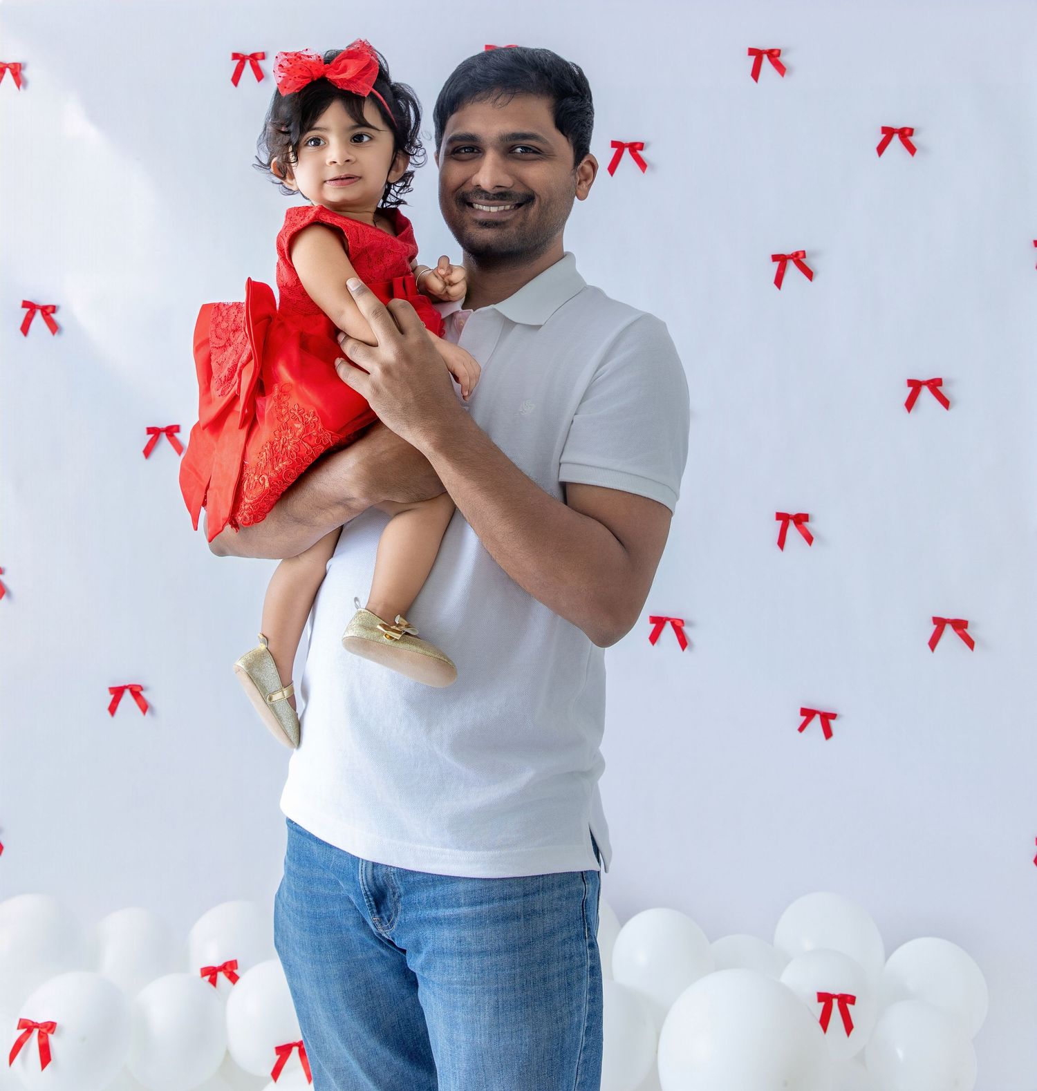 A family photoshoot featuring playful moments against a white backdrop with red bow accents.