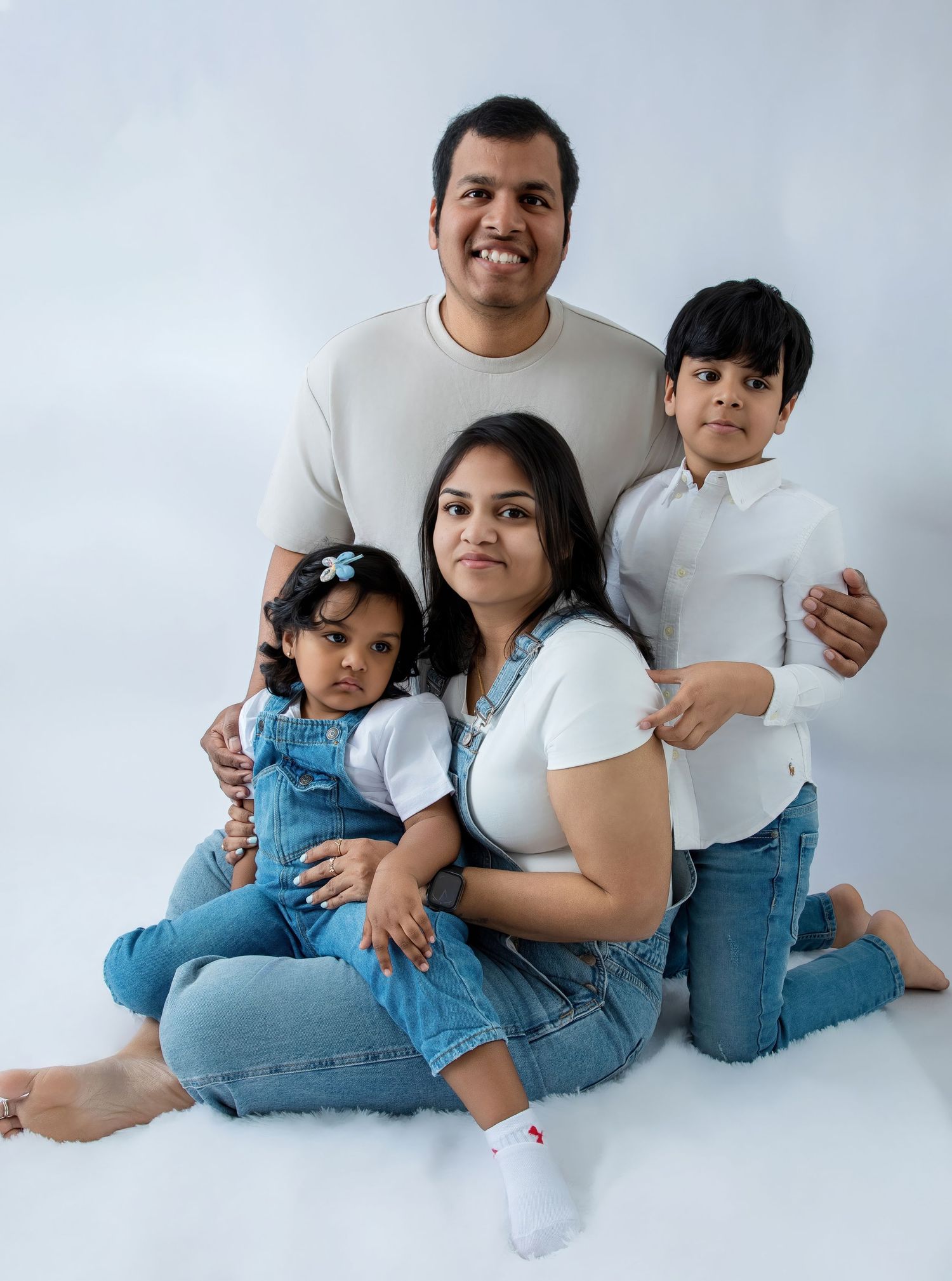 Casual family photo series with denim and white outfits on seamless background.