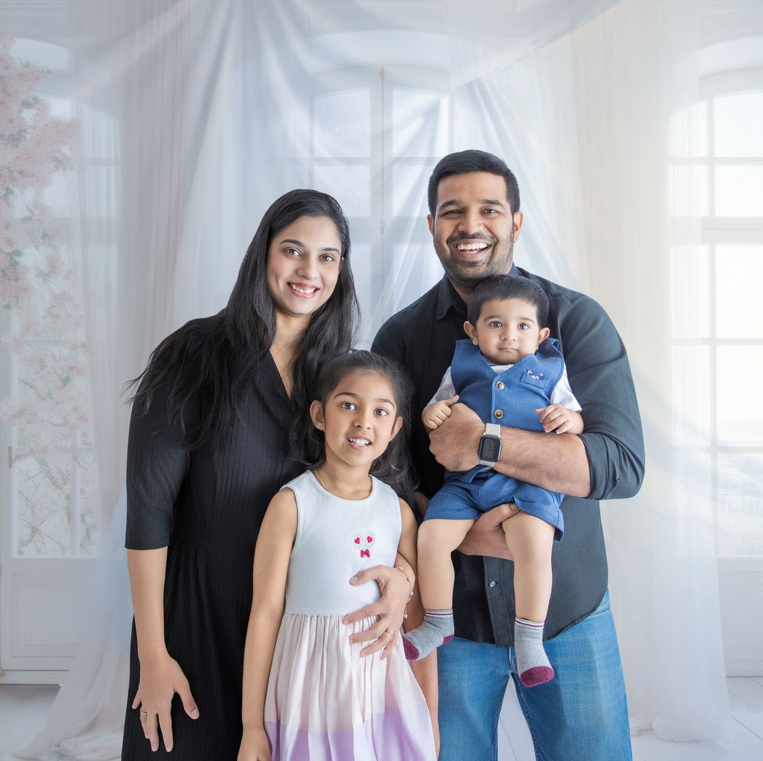 A family of three poses together in a bright white studio setting for a casual portrait session.