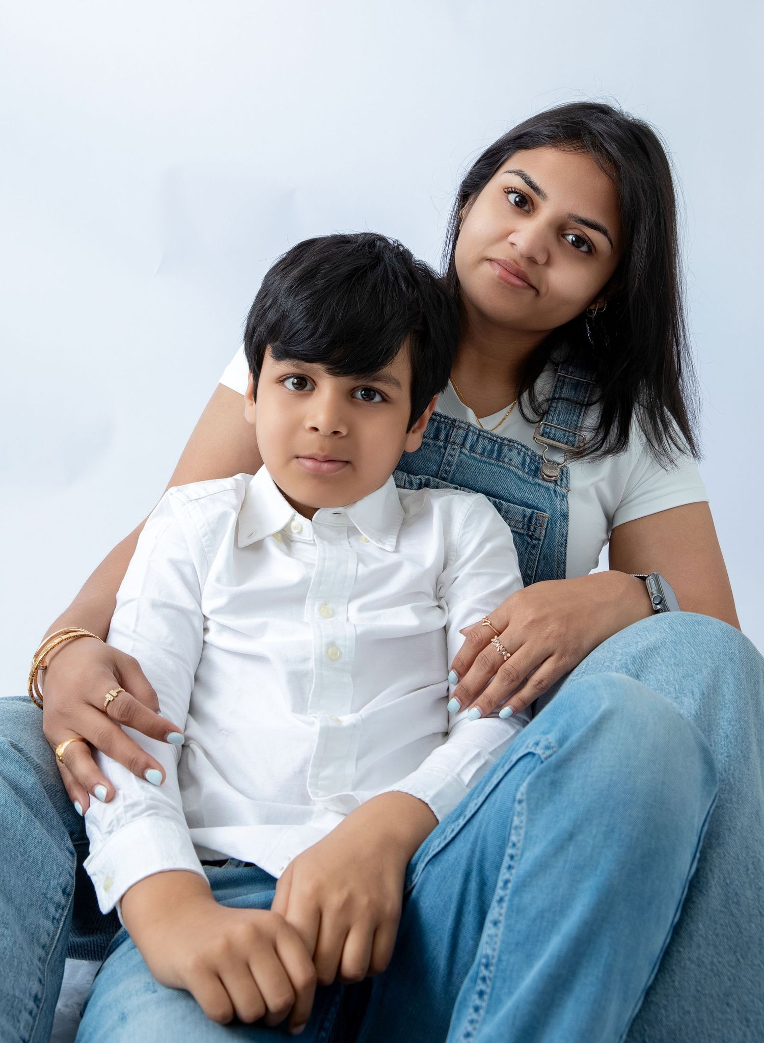 A casual family photo series against white backdrop featuring matching denim and white outfits.