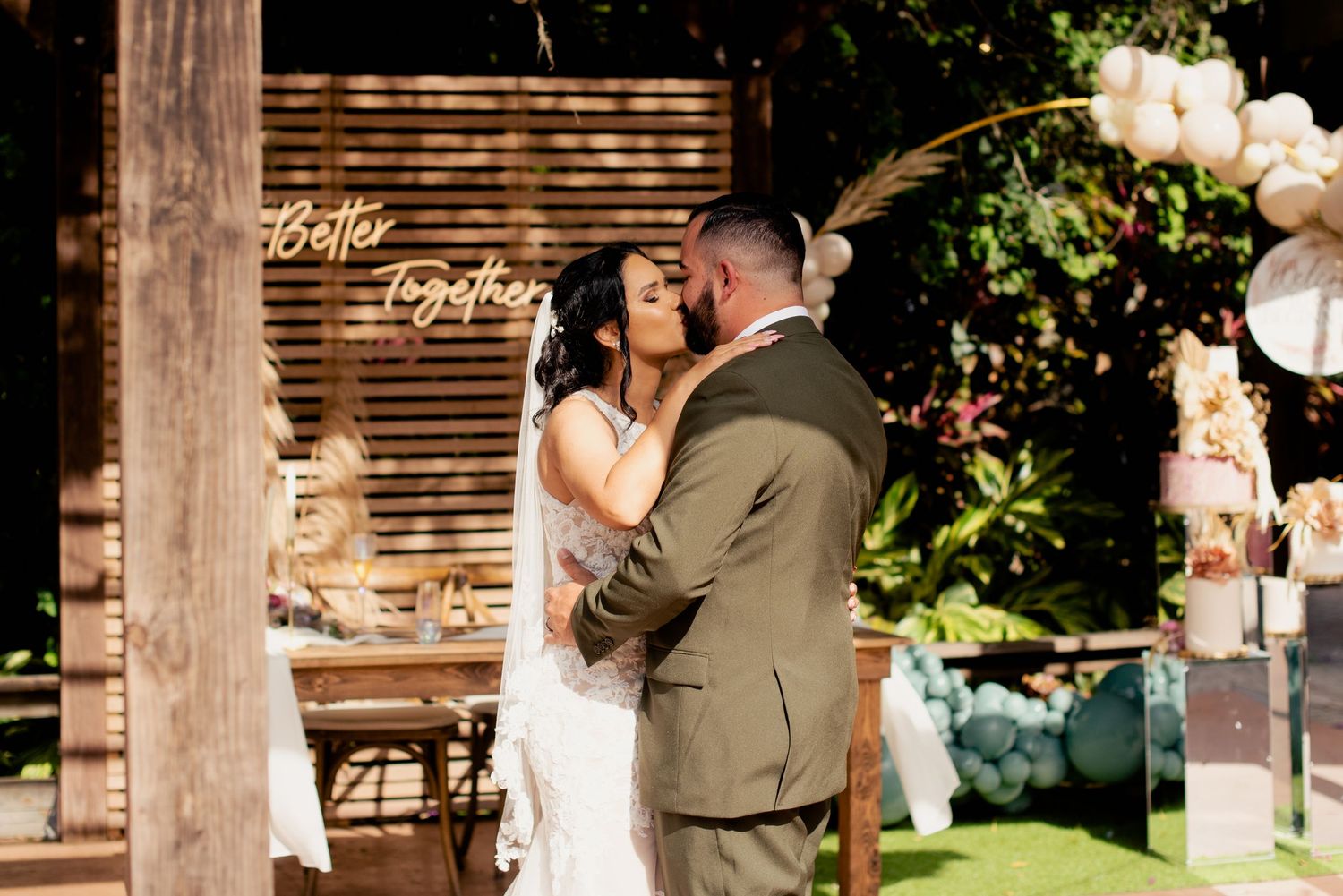 A couple shares romantic moments at their wedding celebration with balloon decorations in the background.