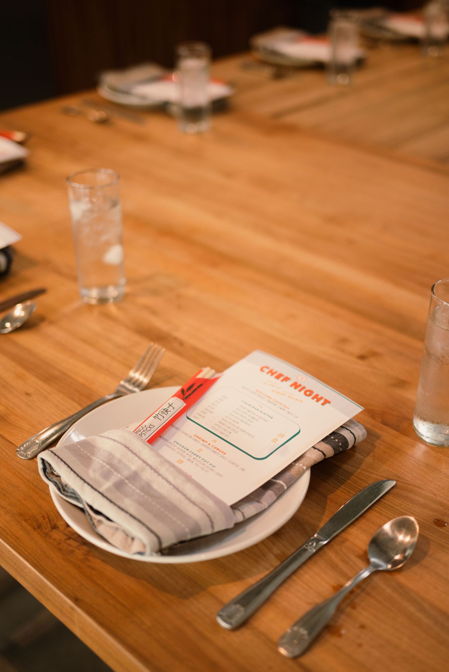 Place settings with menus and silverware arranged on wooden tables.