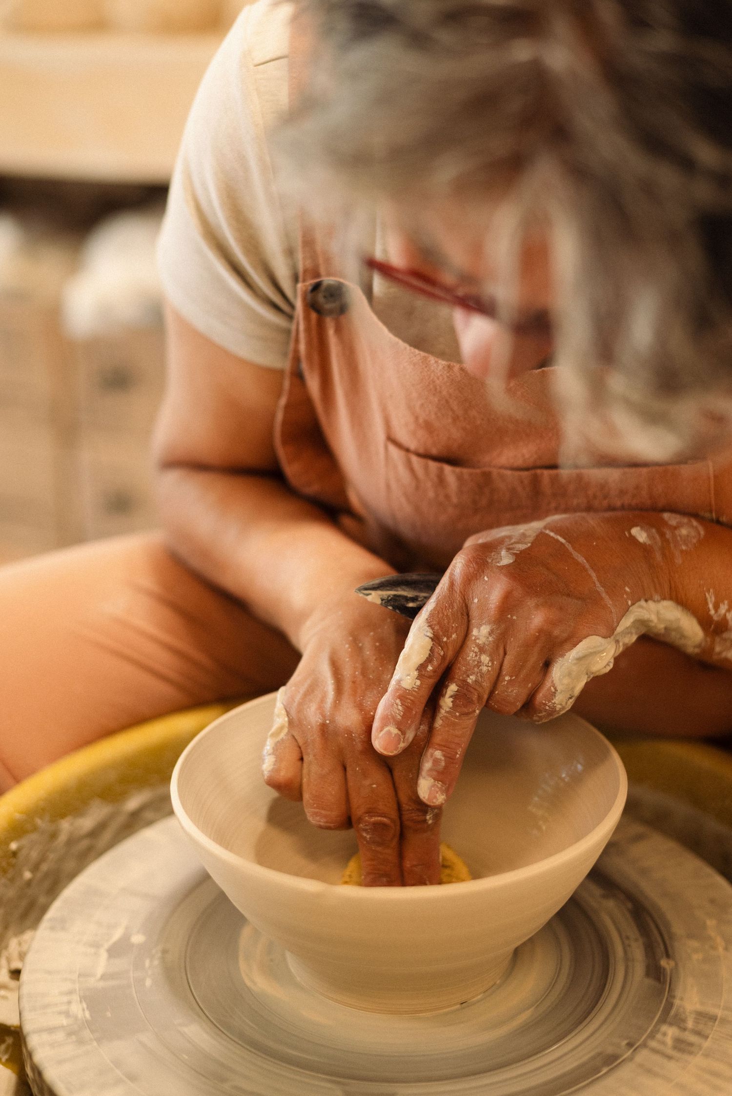 Close-up of hands forming clay bowl on spinning pottery wheel.