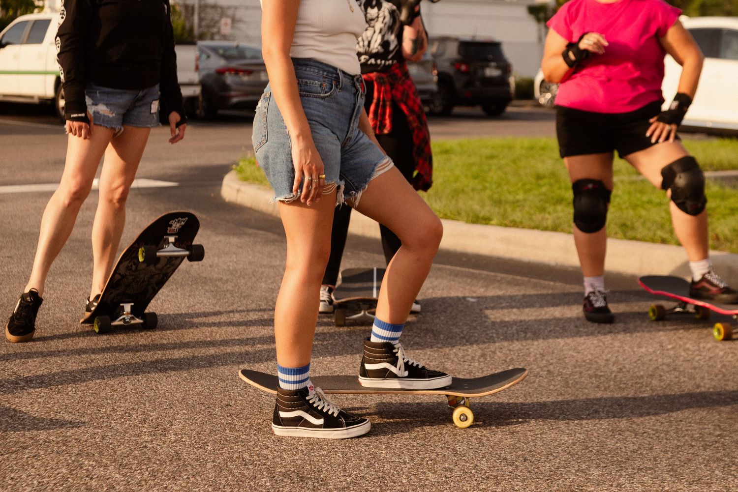 Close-up of feet and skateboard wheels rolling on pavement during sunset.