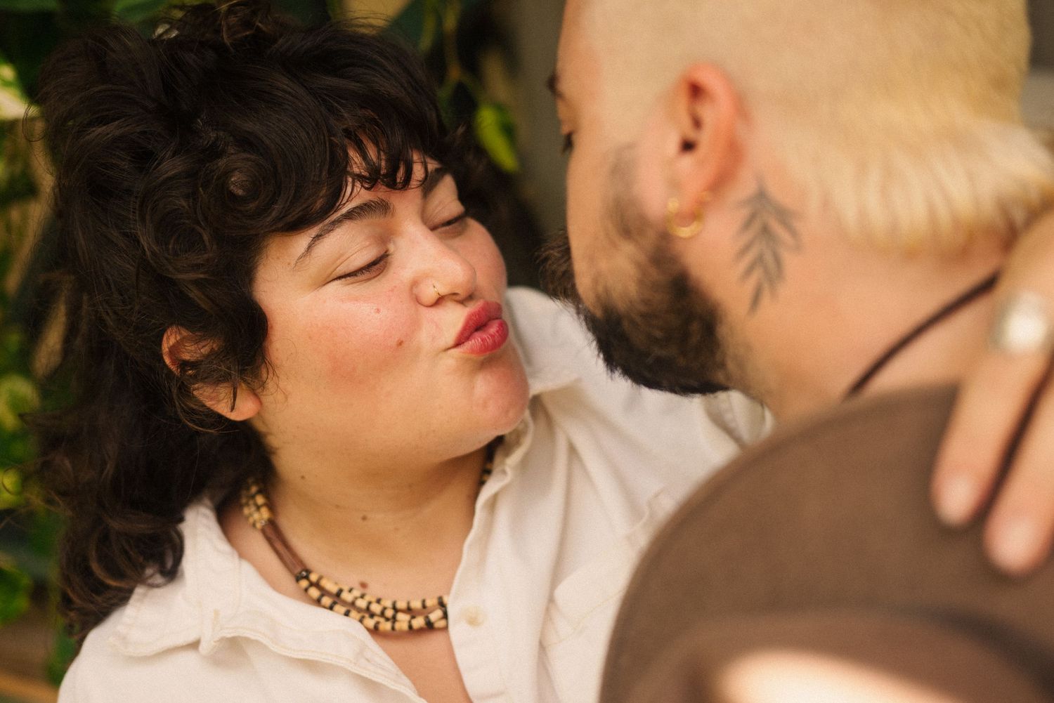 An intimate couple's photoshoot in a garden setting with natural lighting.