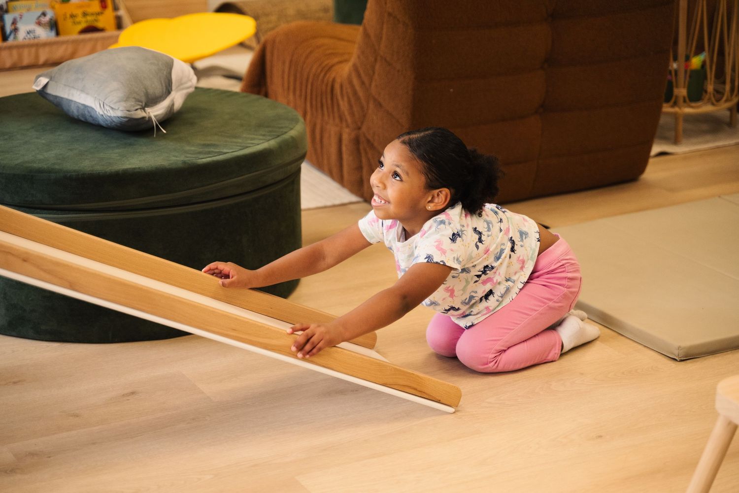 Indoor play space with wooden climbing equipment and exercise mats.