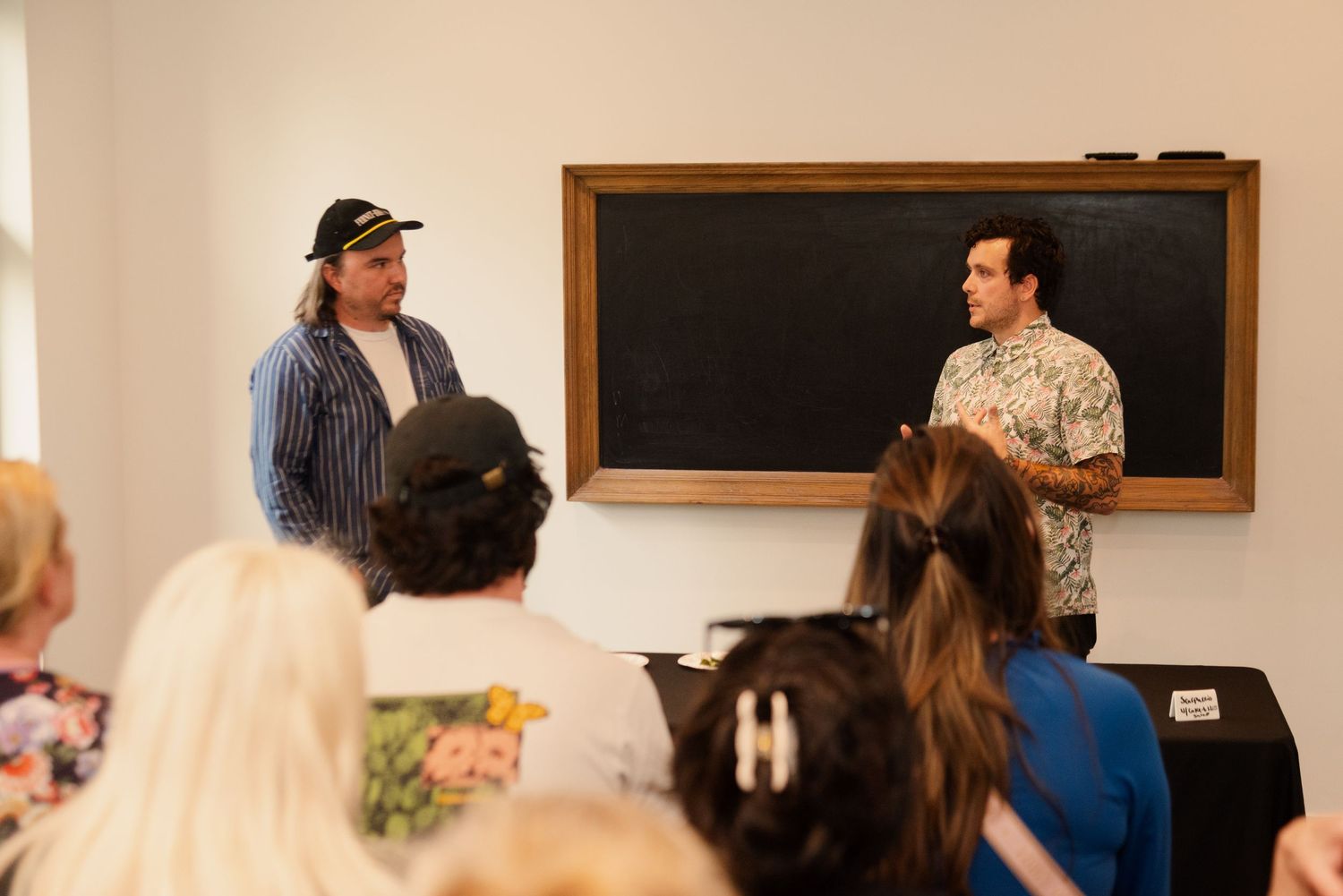 Speaker delivering a presentation in front of a blackboard to an engaged audience.