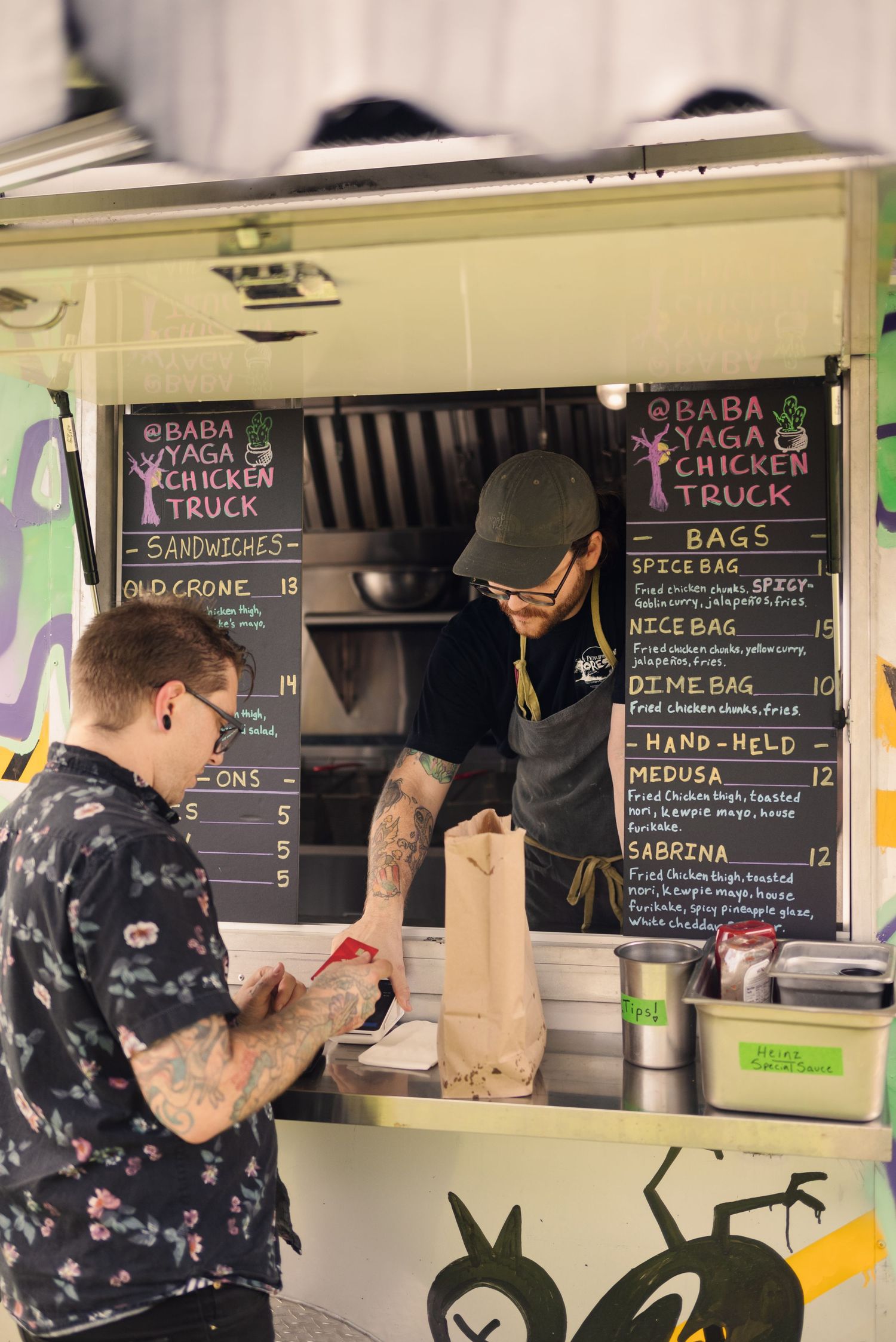 Food truck service window with chalkboard menu and customers placing orders.