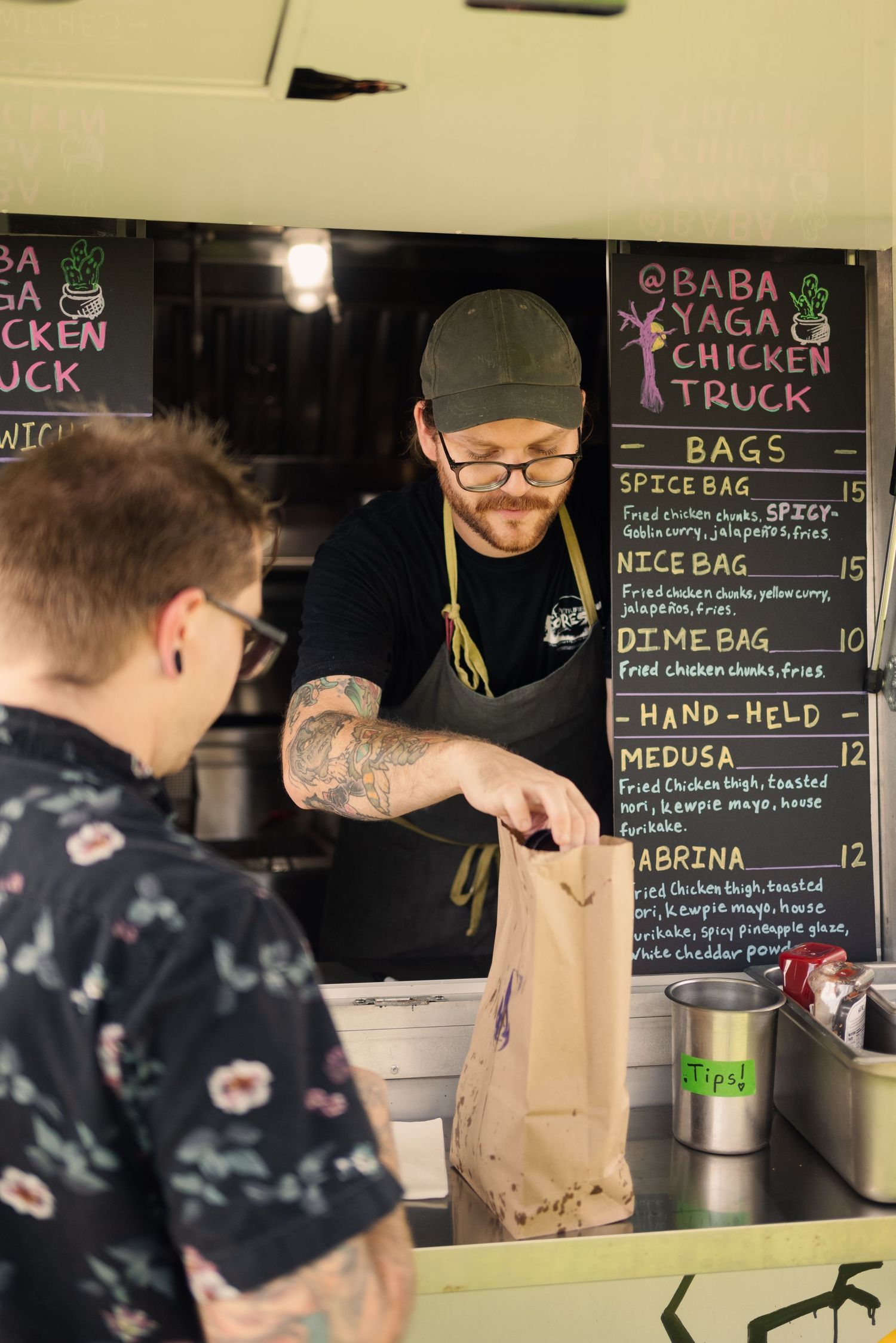Customers ordering from a food truck window with menu board visible.
