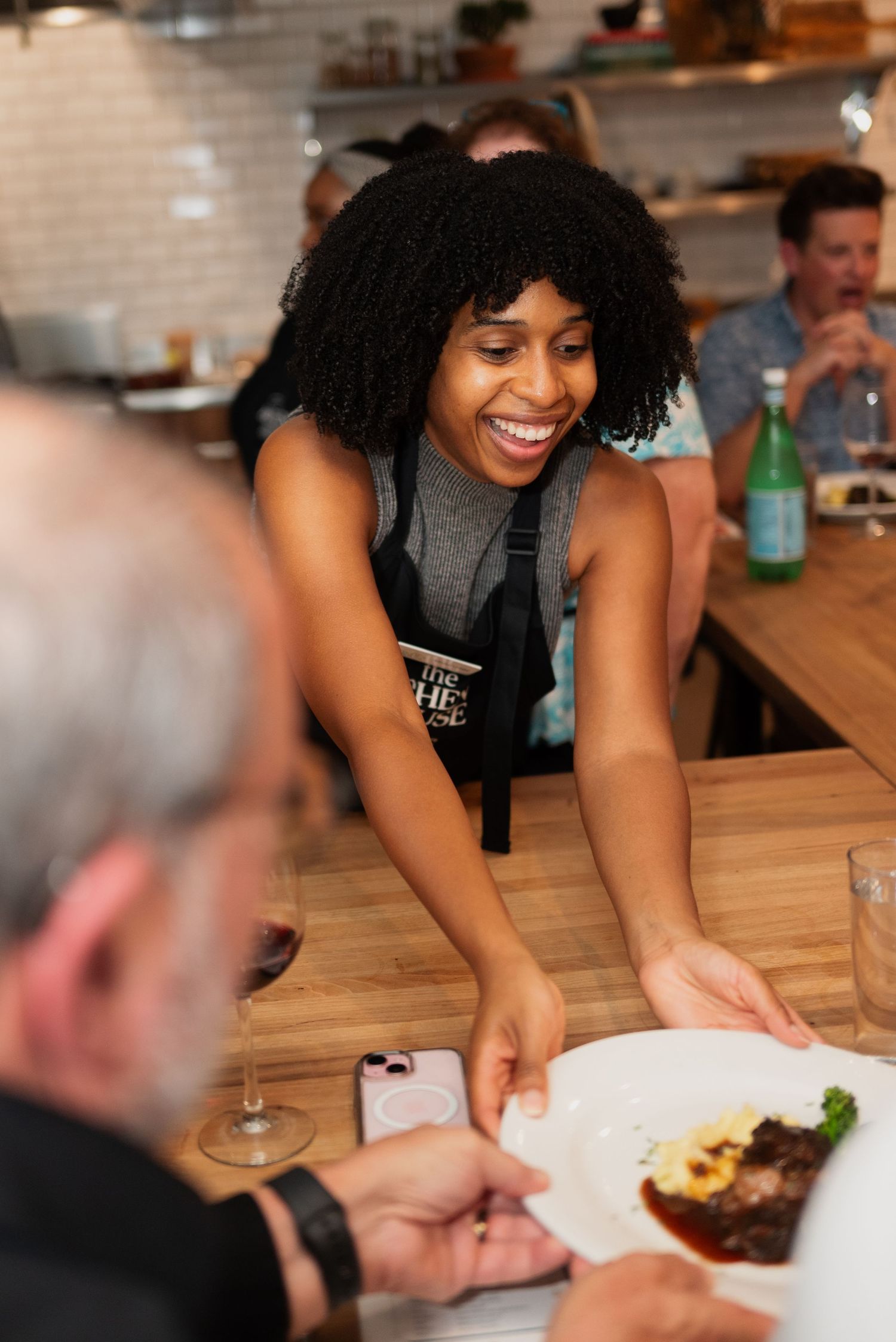 Diners enjoying a meal at a restaurant with white subway tile walls and wooden tables.
