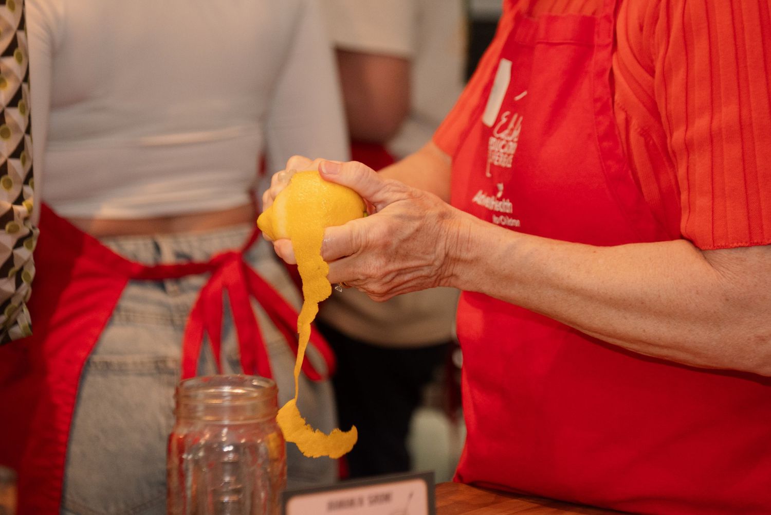 People in red aprons working with fresh ingredients during a cooking class.