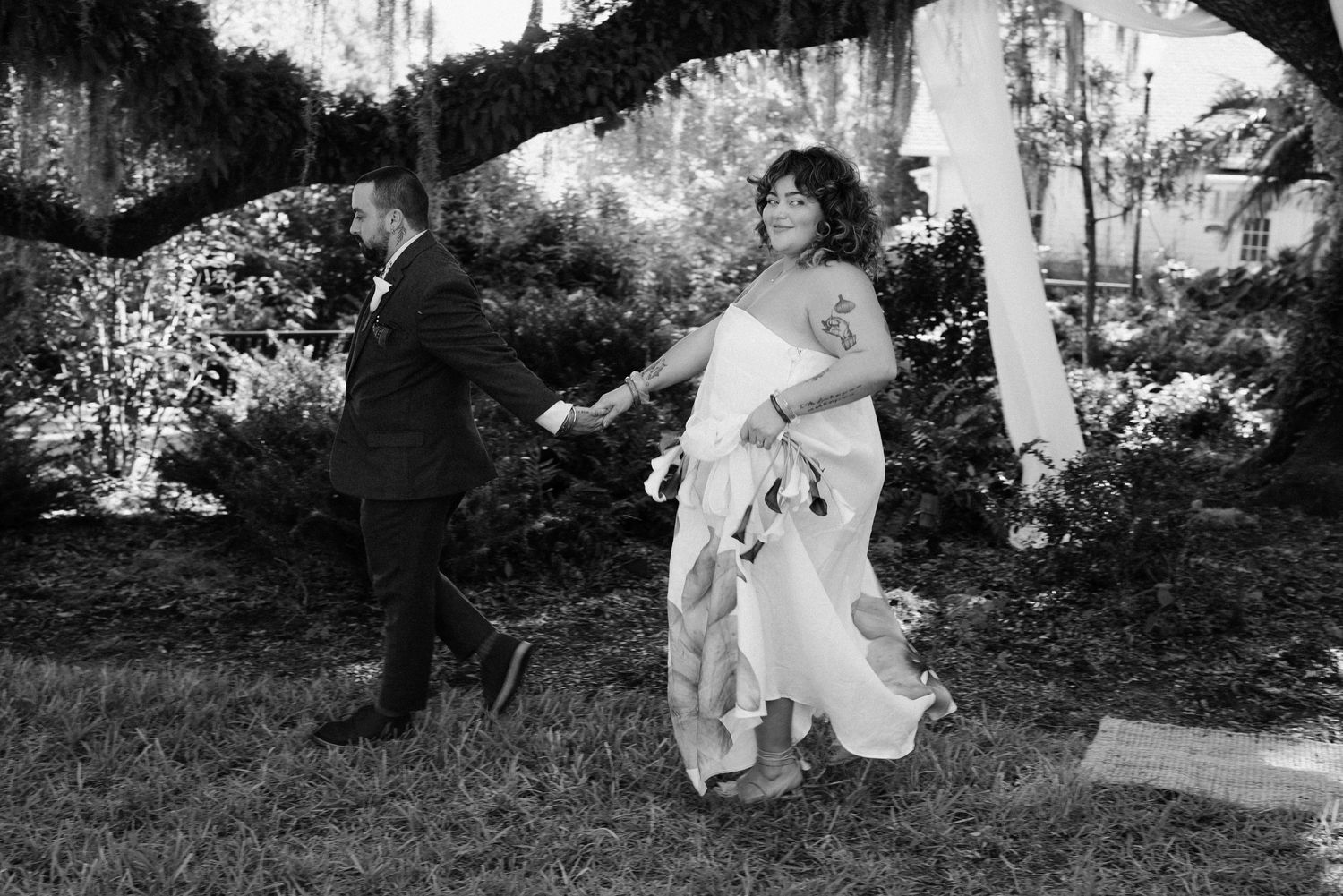 A couple dances together under a tree branch in a black and white photograph.