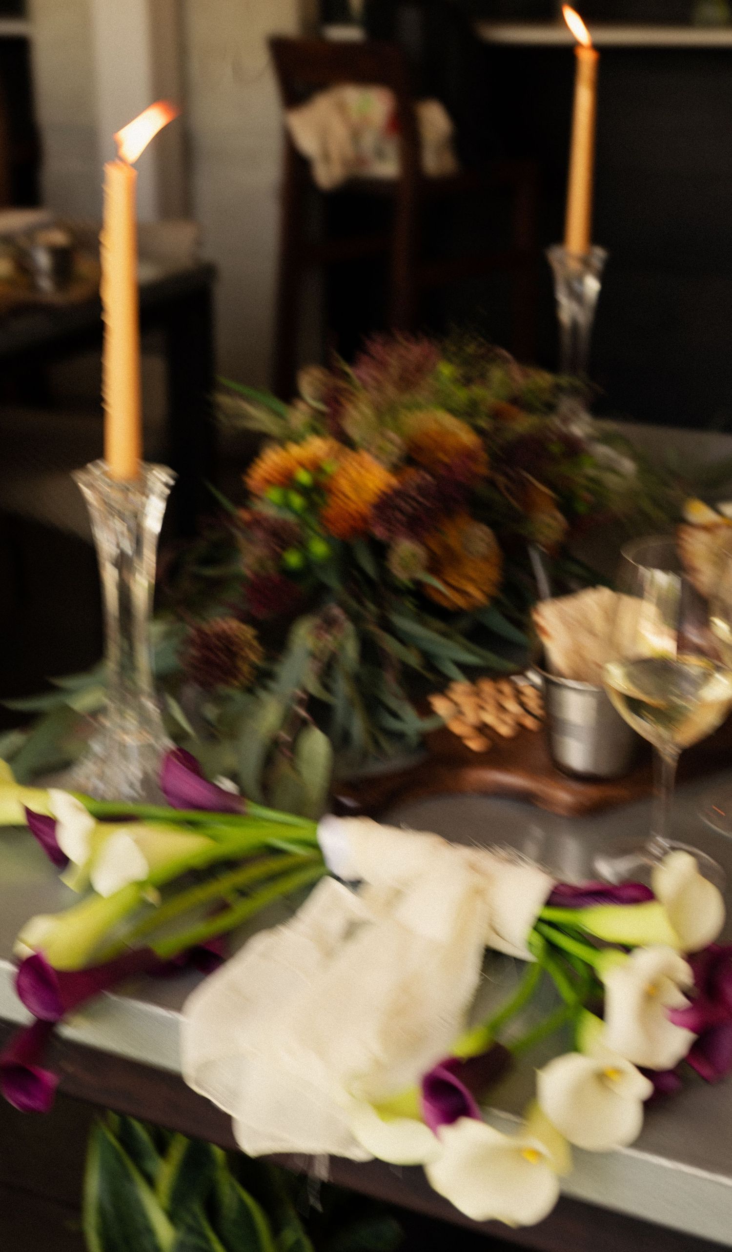 Elegant table setting with white orchids, purple flowers and tall candles creating a romantic ambiance.