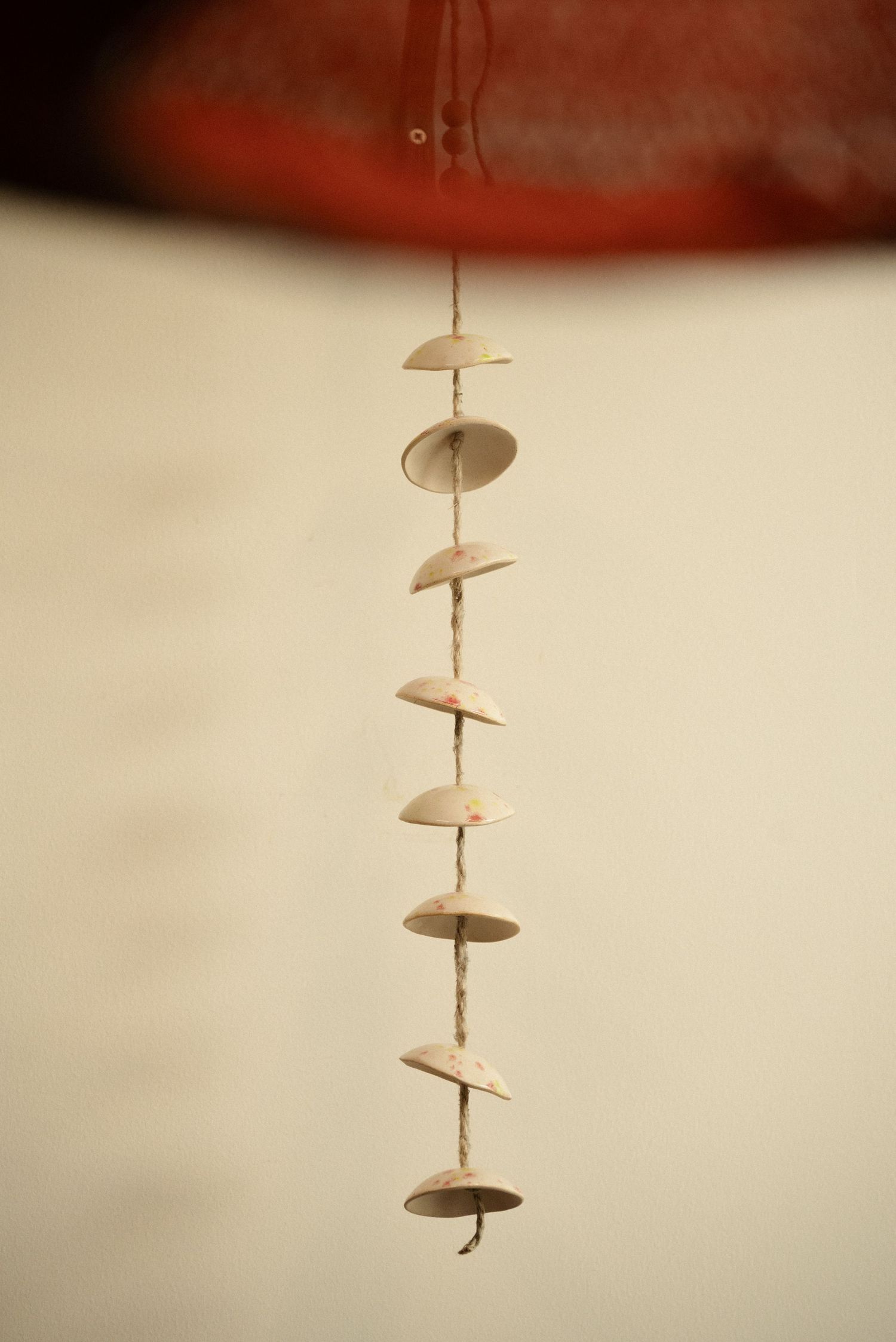 Decorative hanging mobile with circular wooden discs on string against light background.