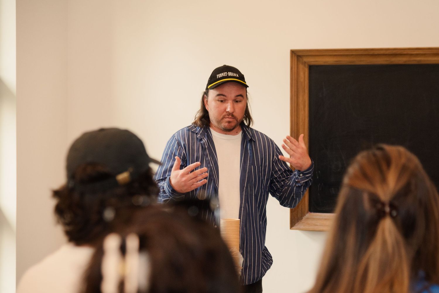 Speaker gesturing while presenting to an attentive audience in a modern meeting room.