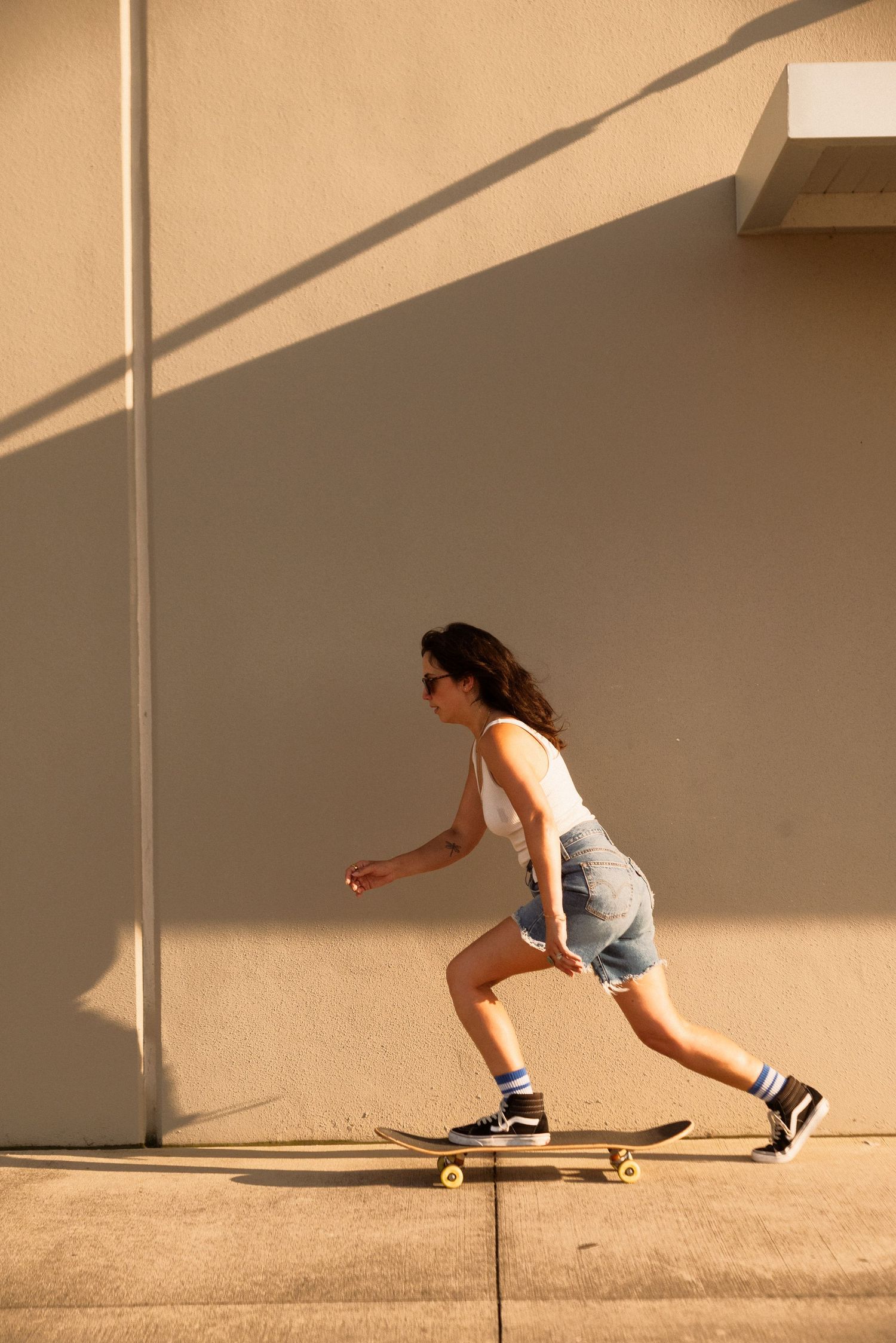 Sequence showing skateboarding moves against a beige wall with dramatic shadow patterns.