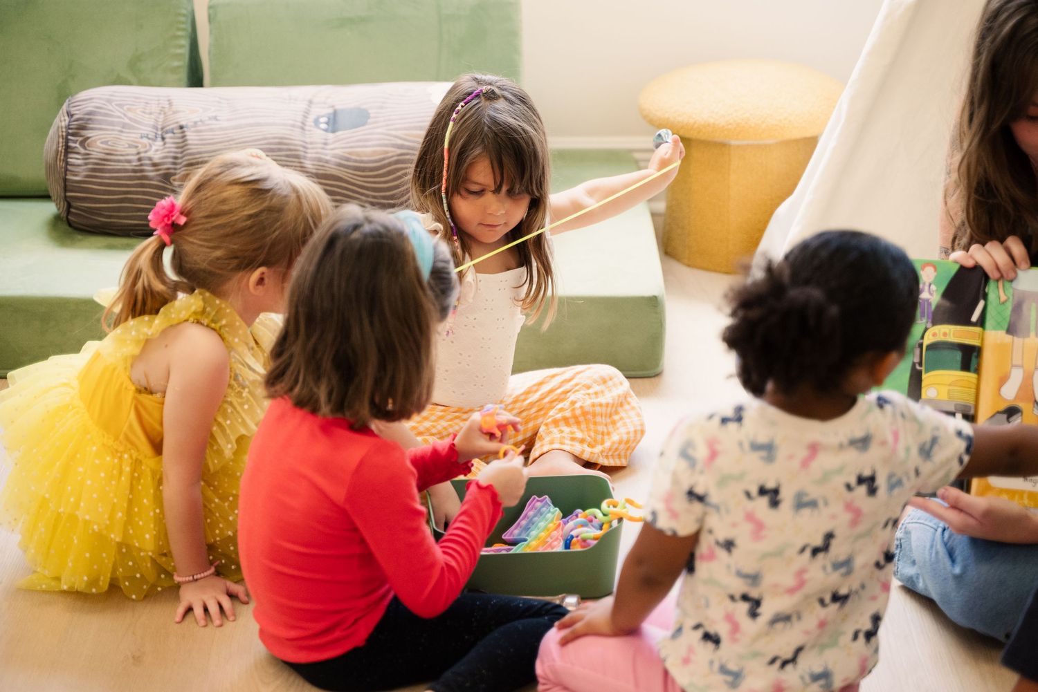 Children sitting on floor engaged in group activity with toys.