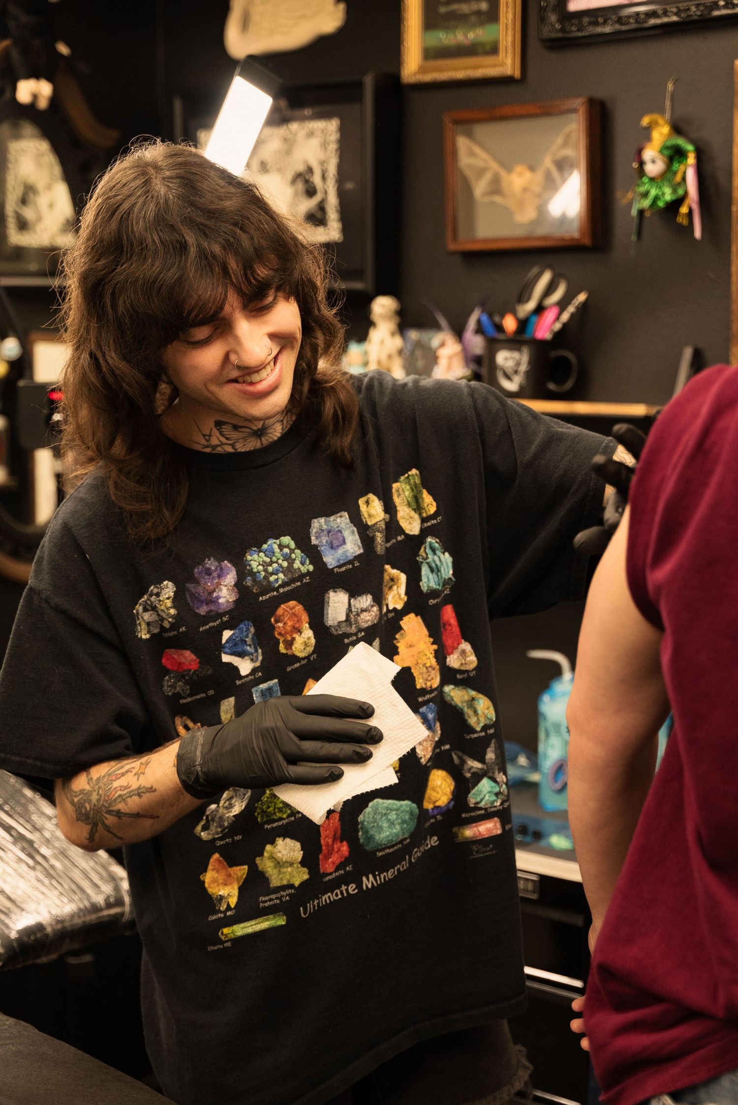 Tattoo artist wearing black gloves shows colorful artwork in a studio.