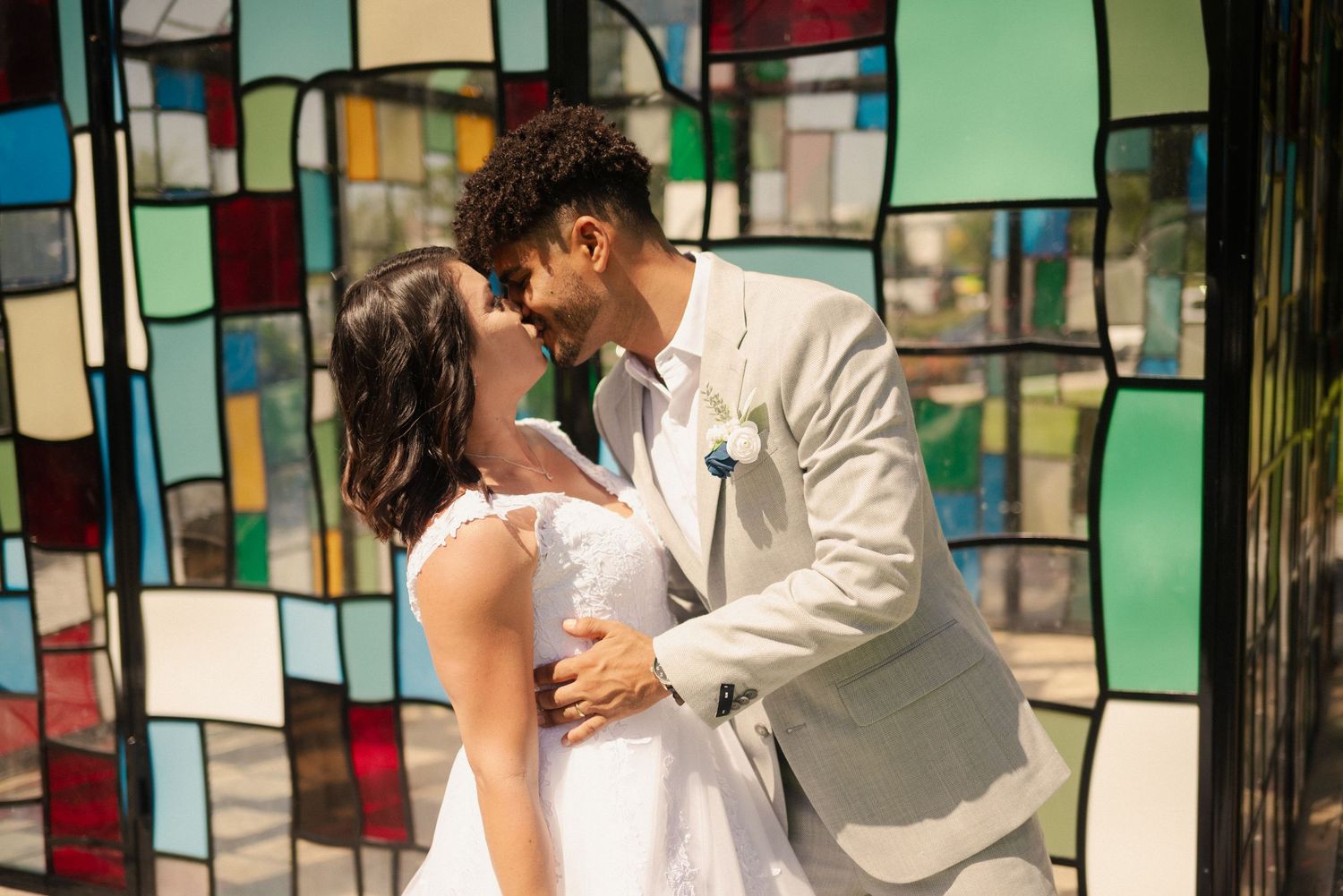Wedding celebration in front of a vibrant stained glass chapel structure.