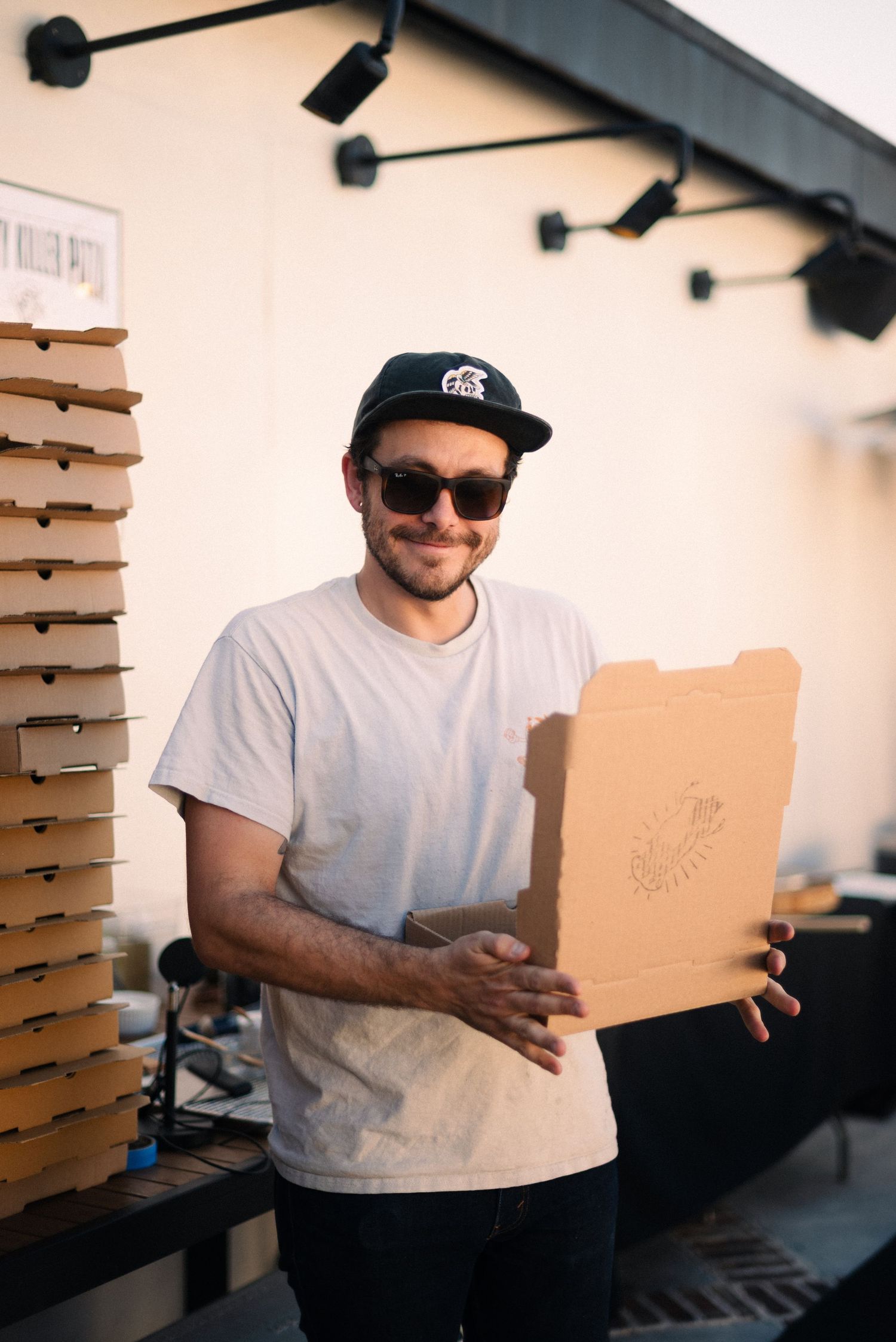 Person in white t-shirt and cap examining cardboard packaging materials.