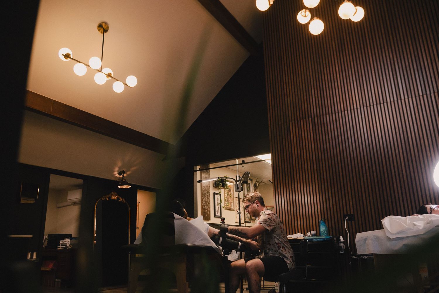 Modern chandelier lighting fixtures illuminate a wood-paneled ceiling.