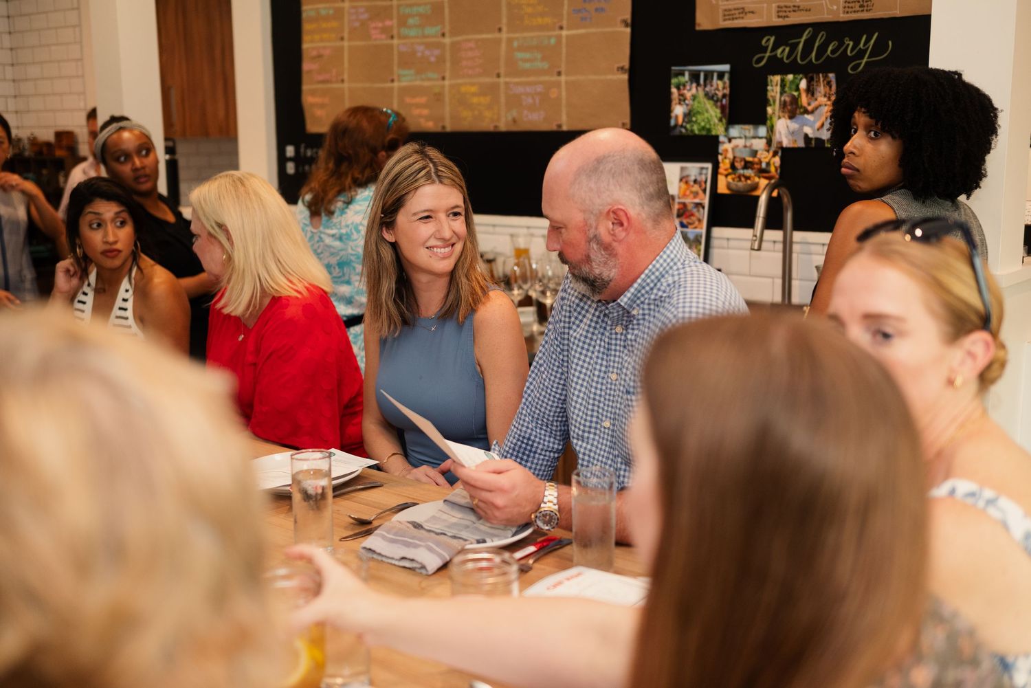 Diners enjoying a meal and conversation at a communal table in a casual restaurant setting.