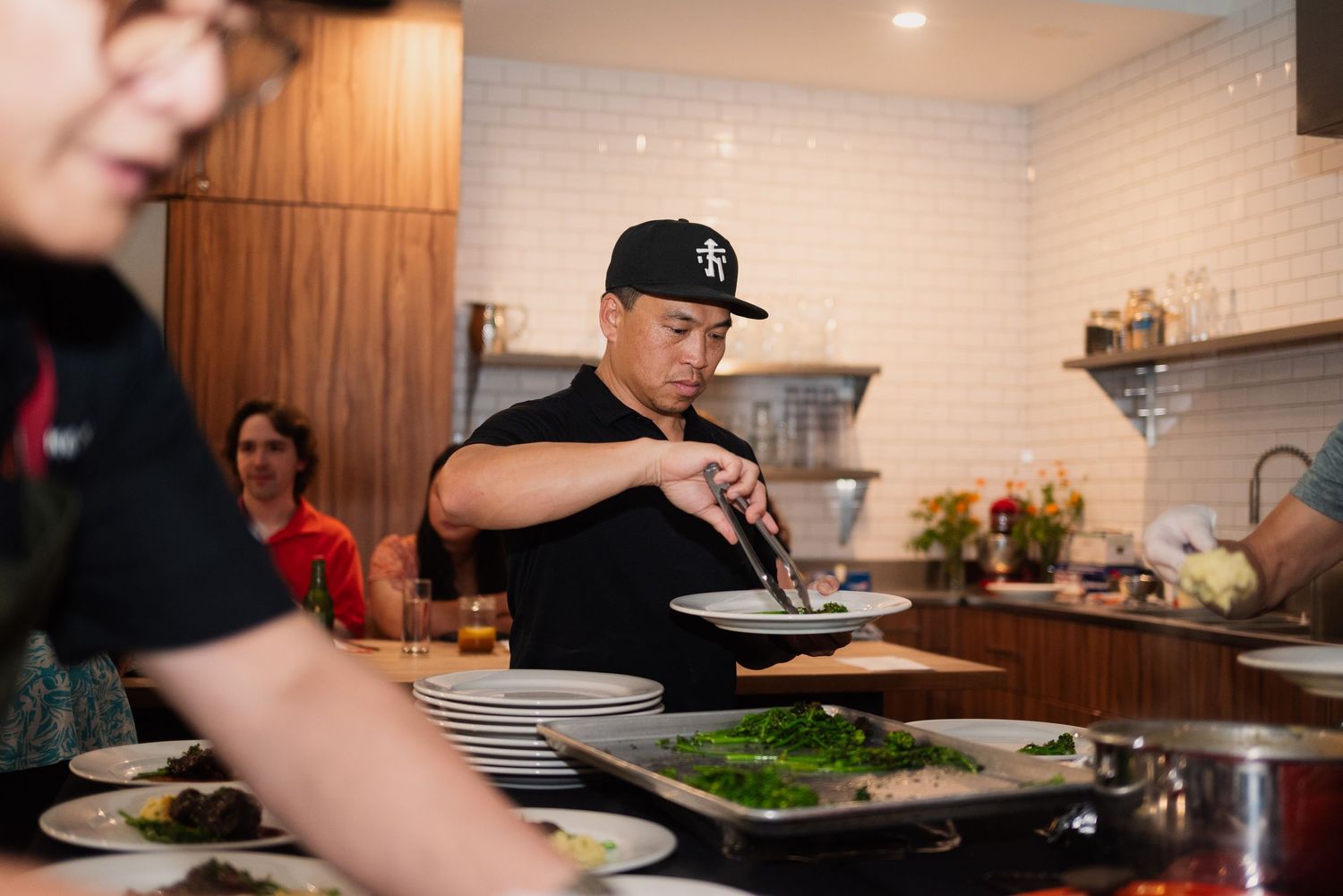 Chefs in a restaurant kitchen plating dishes with precision and care on wooden countertops.