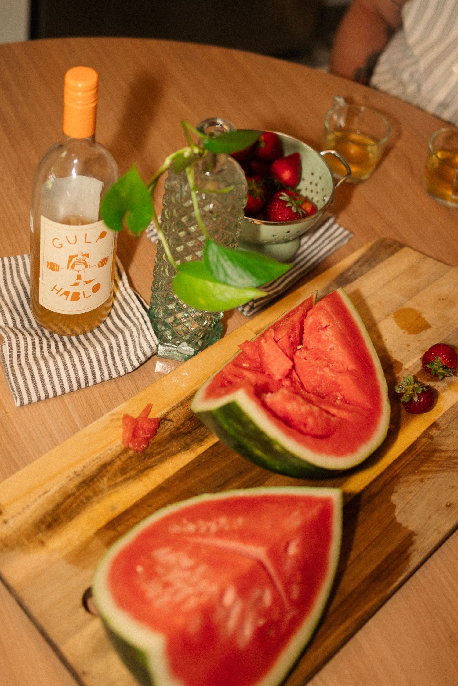 Fresh watermelon slices and wine bottle on wooden cutting board with summer drinks.