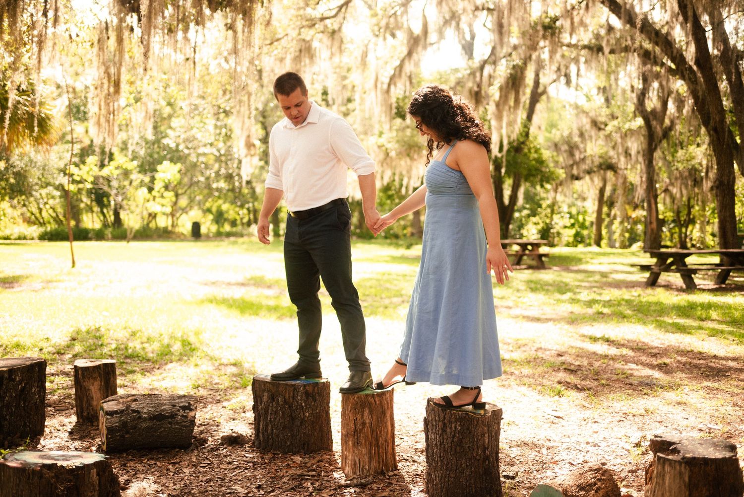 Couple walking together through a sun-dappled garden path with Spanish moss overhead.