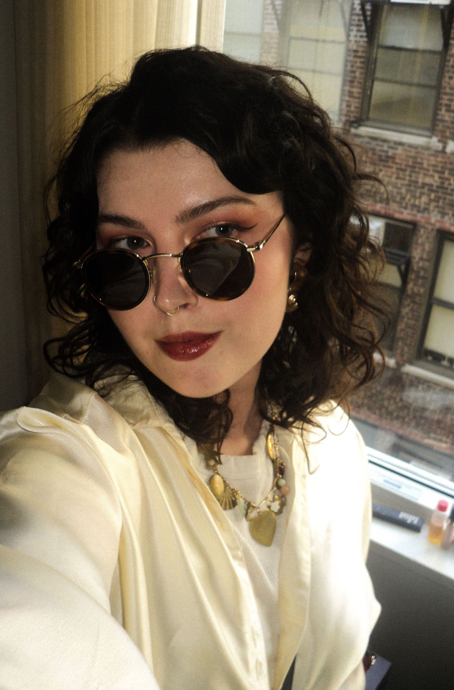 A fashionable selfie featuring round sunglasses and dark lipstick.