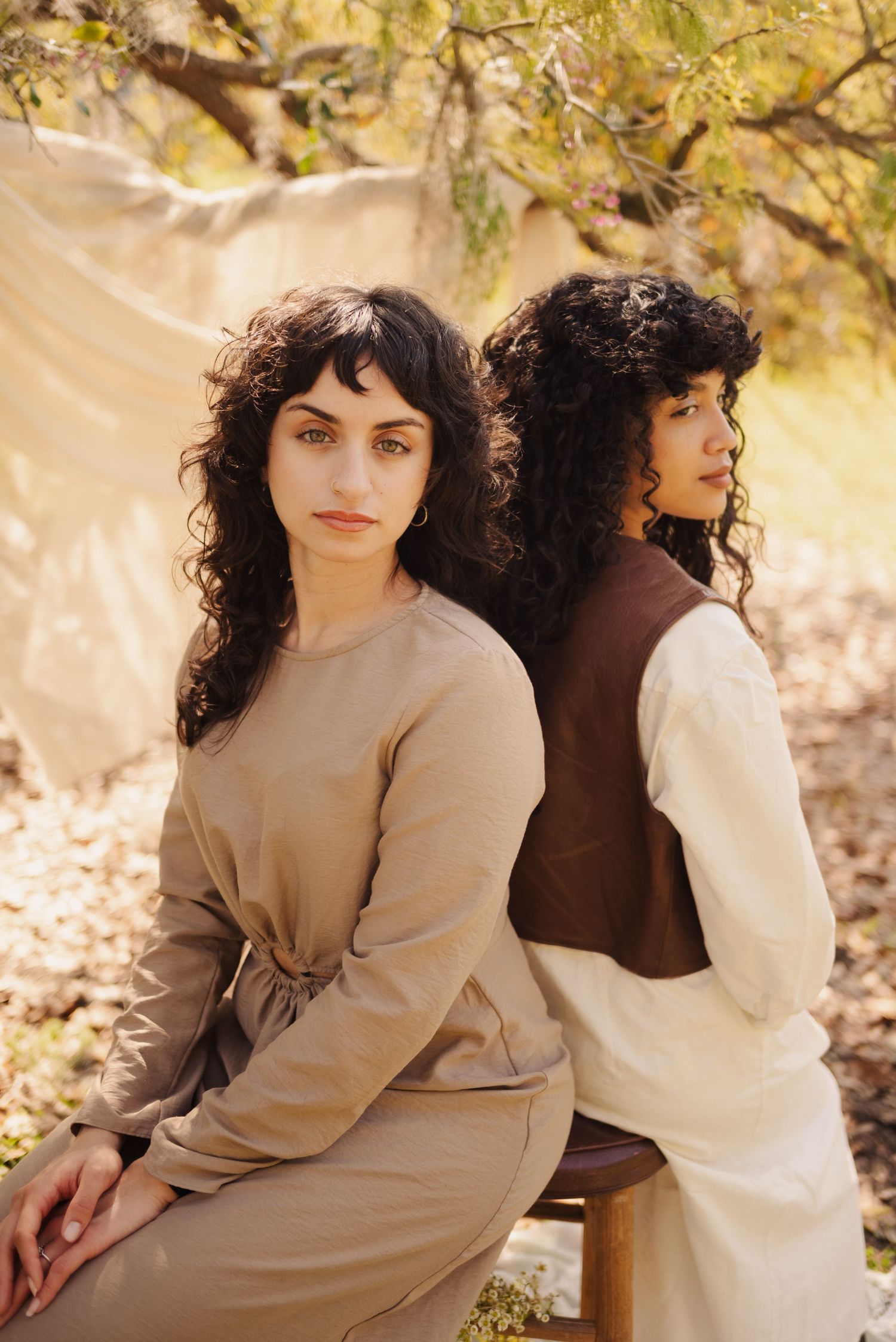 Romantic autumn photoshoot with neutral tones and soft natural lighting among fallen leaves.
