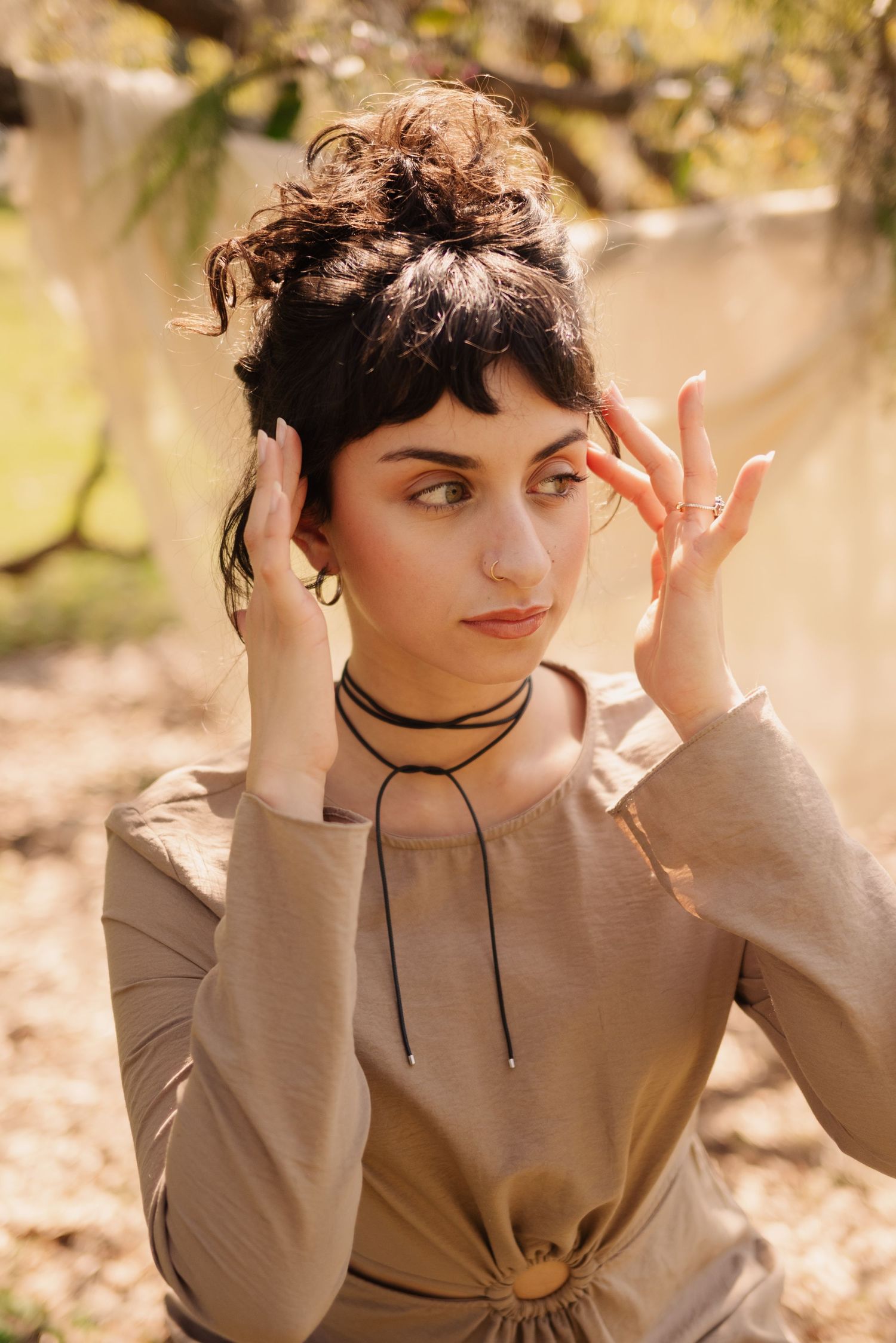 A vintage-inspired fashion portrait in warm tones featuring a tan dress and choker necklace in an outdoor autumn setting.