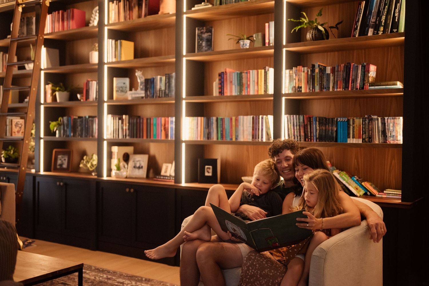A warm-lit library setting with people lounging on comfortable furniture.