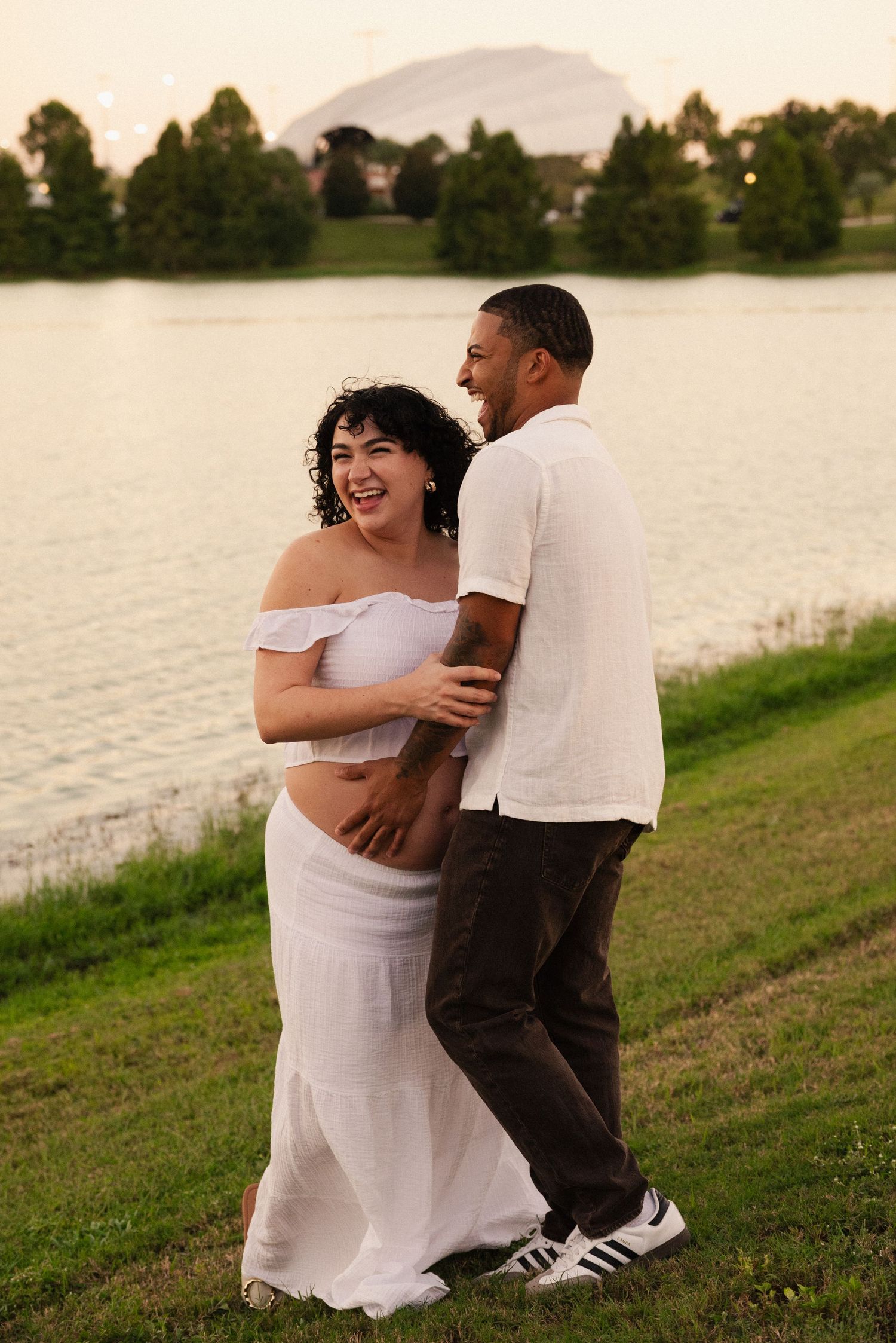 Lakeside maternity photoshoot captures couple's tender moments at dusk.