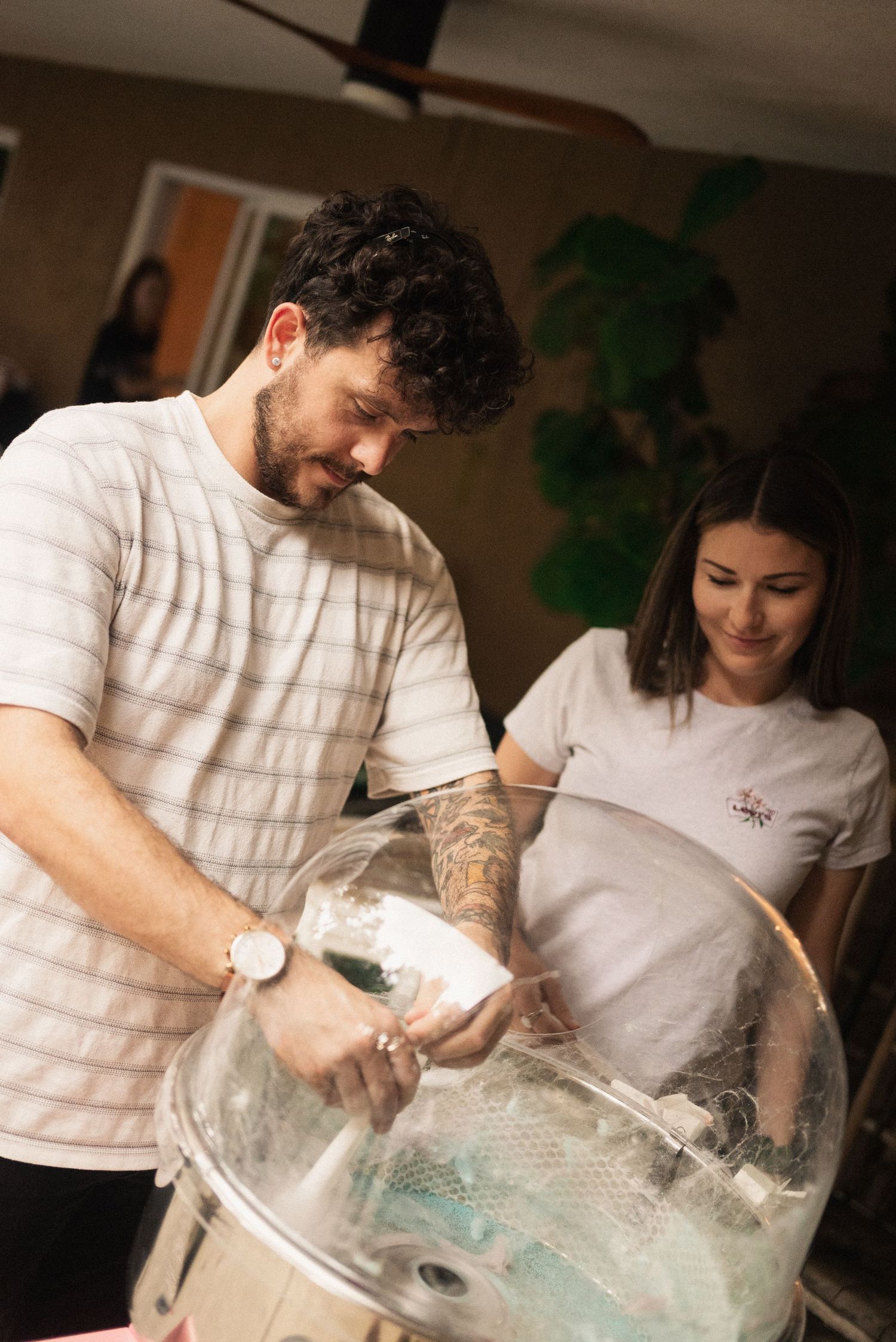 Two people in white shirts working together with clay or dough on a table.