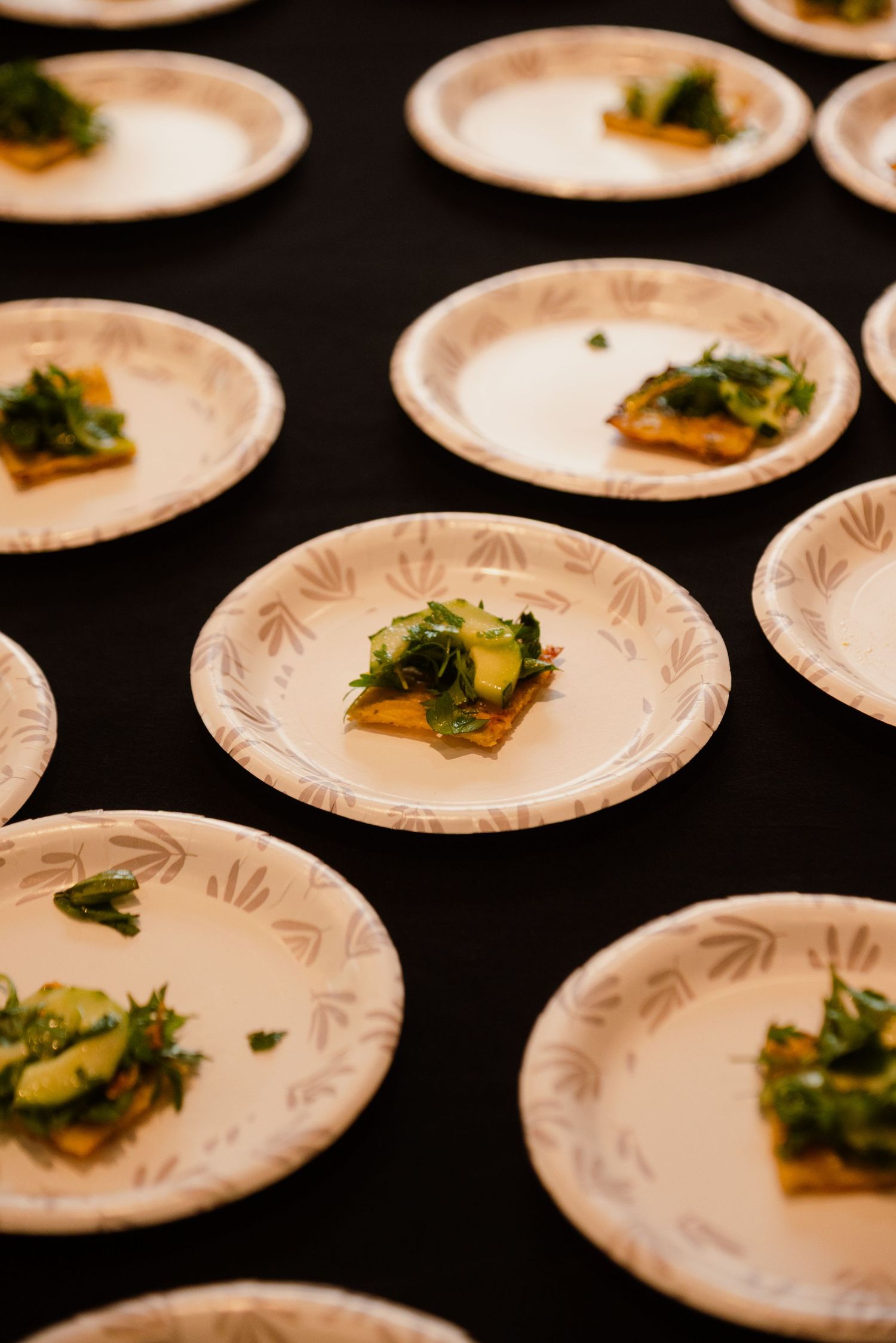 Elegantly plated appetizers on decorative white plates arranged on a black tablecloth.