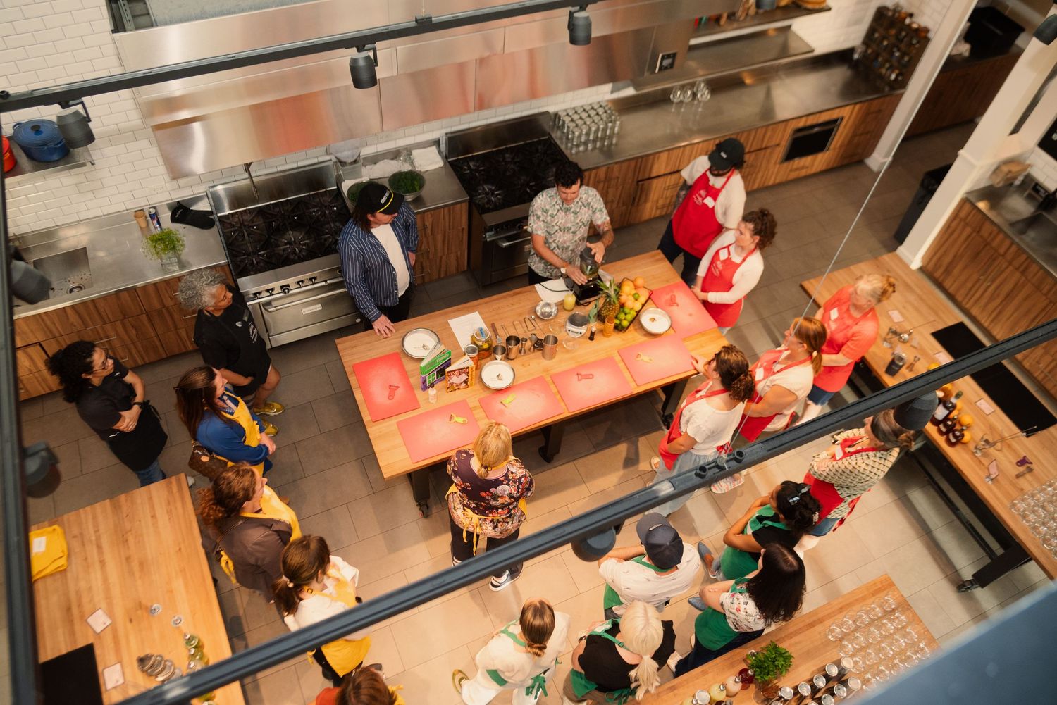 Overhead view of a cooking class with participants seated at long wooden tables.