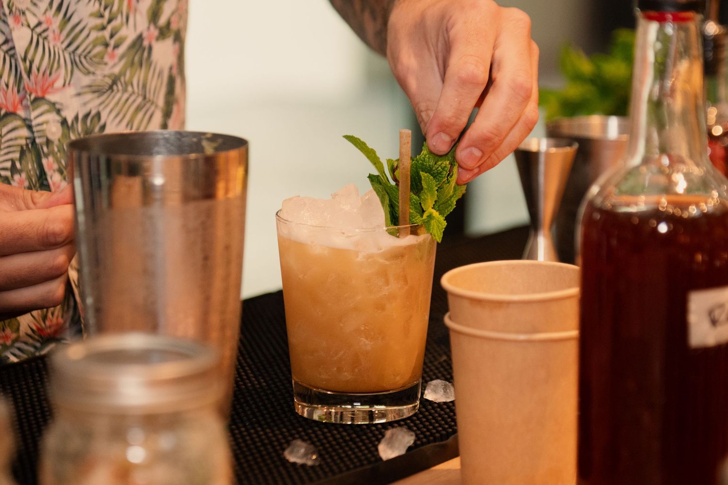 Close-up shots of cocktail preparation showing hands mixing and garnishing drinks during a workshop.