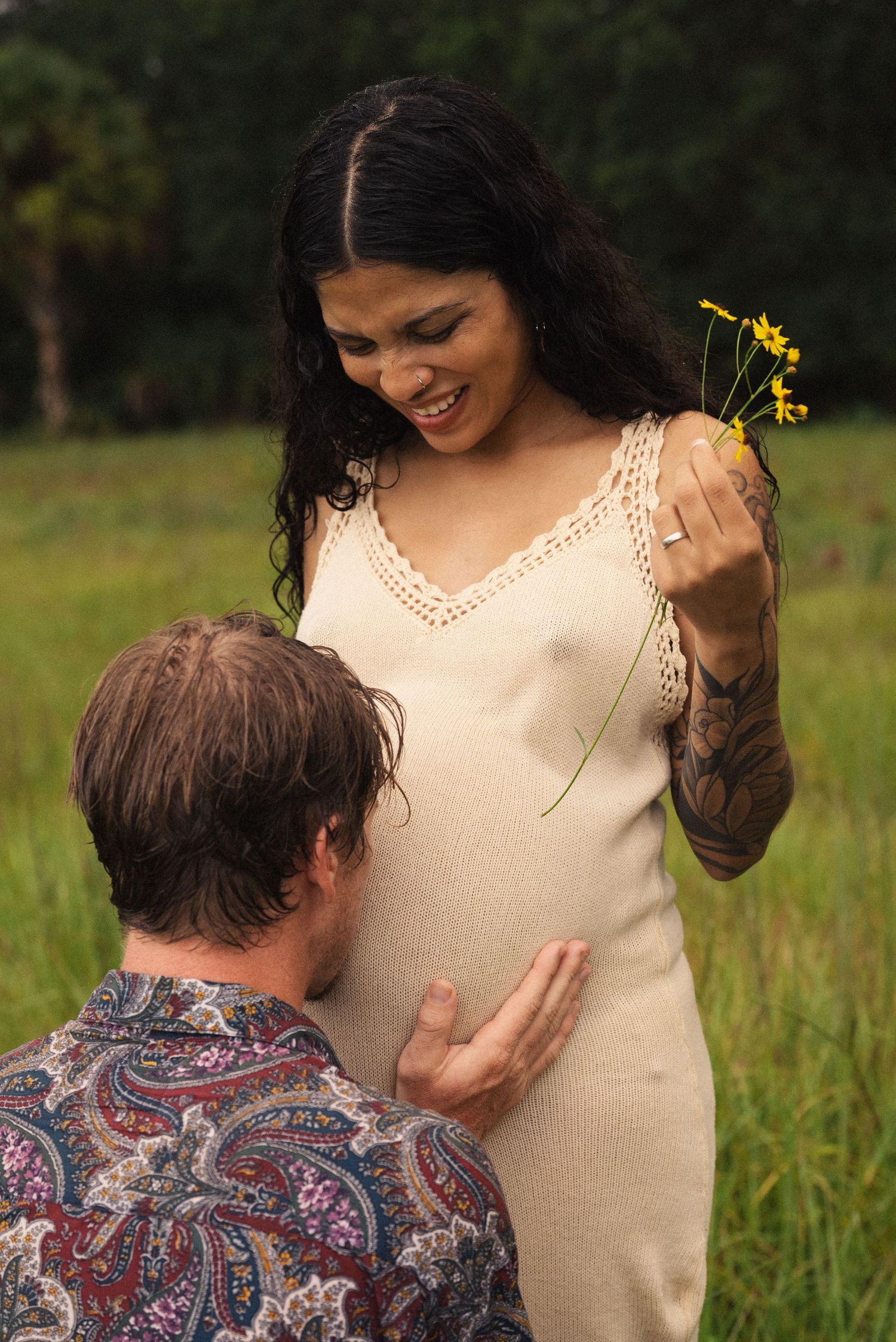 A tender moment captured in a field with yellow flowers and natural lighting.