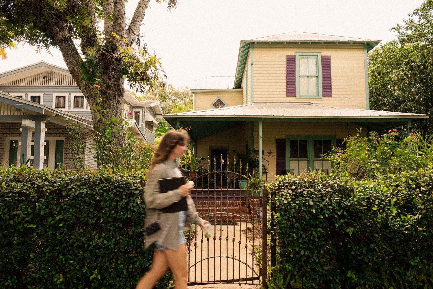 Row of historic houses with porches and landscaping on a residential street.