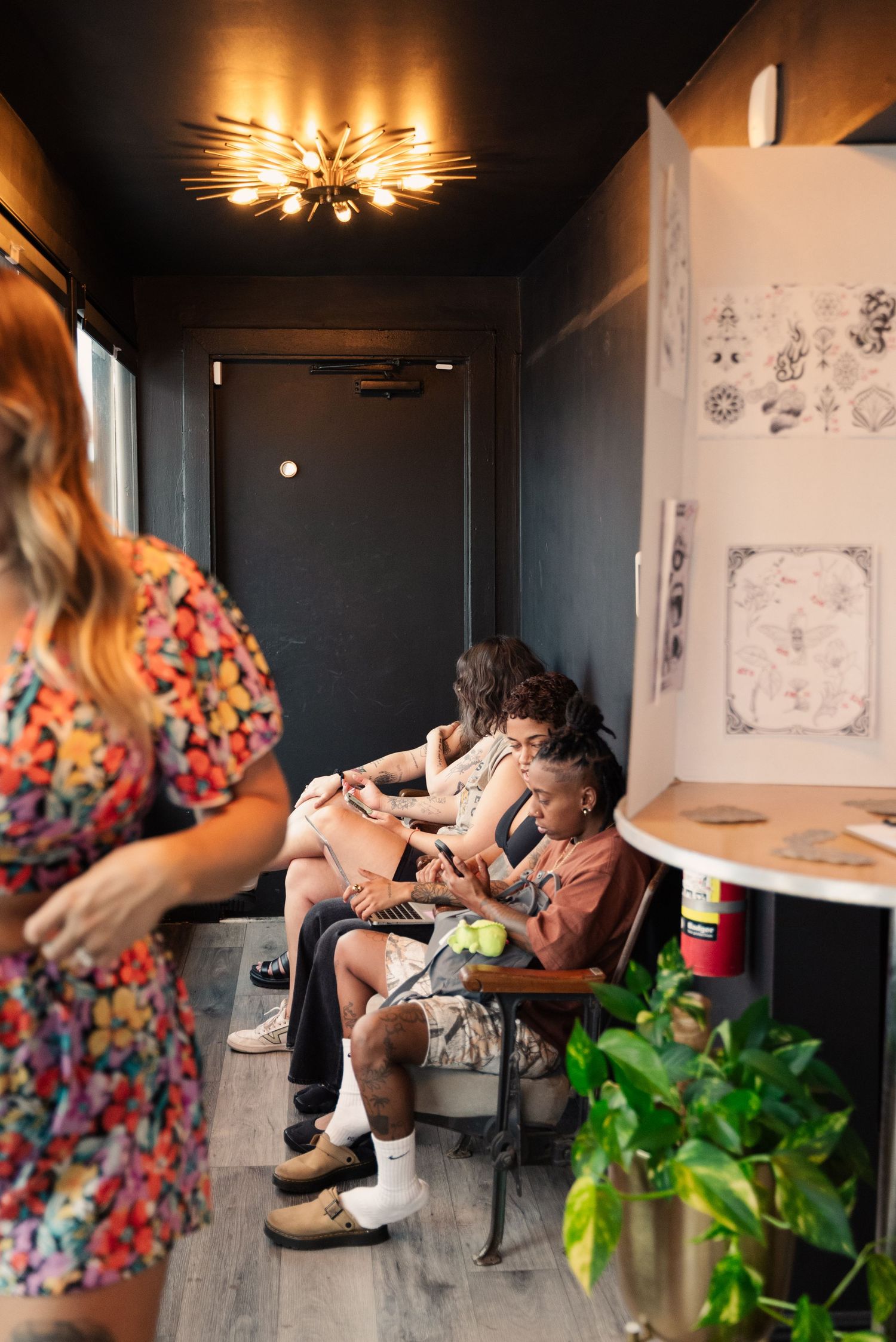 Modern tattoo studio interior with floral wall art and comfortable seating area.