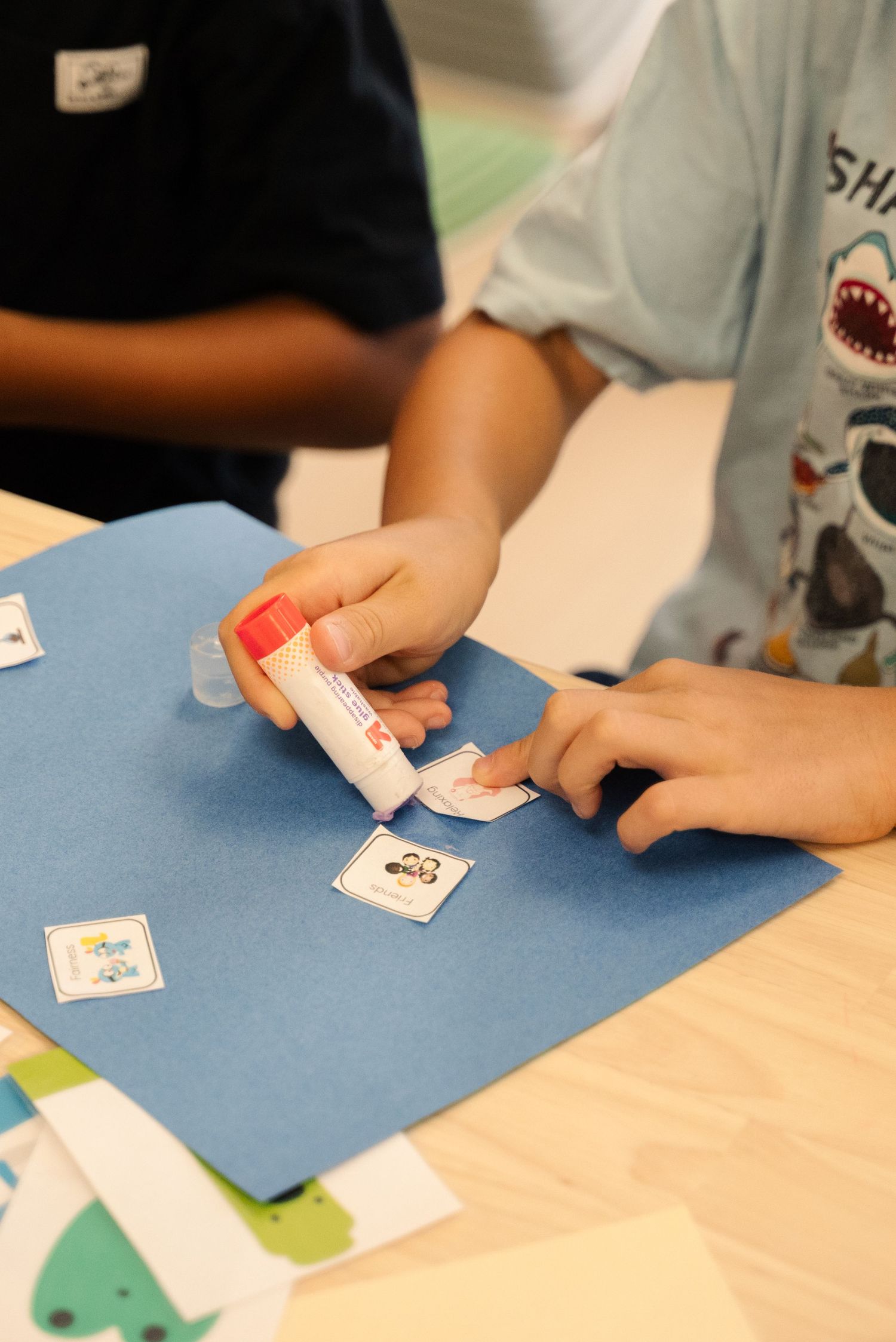 Close-up of hands working with educational cards and materials on a blue surface.