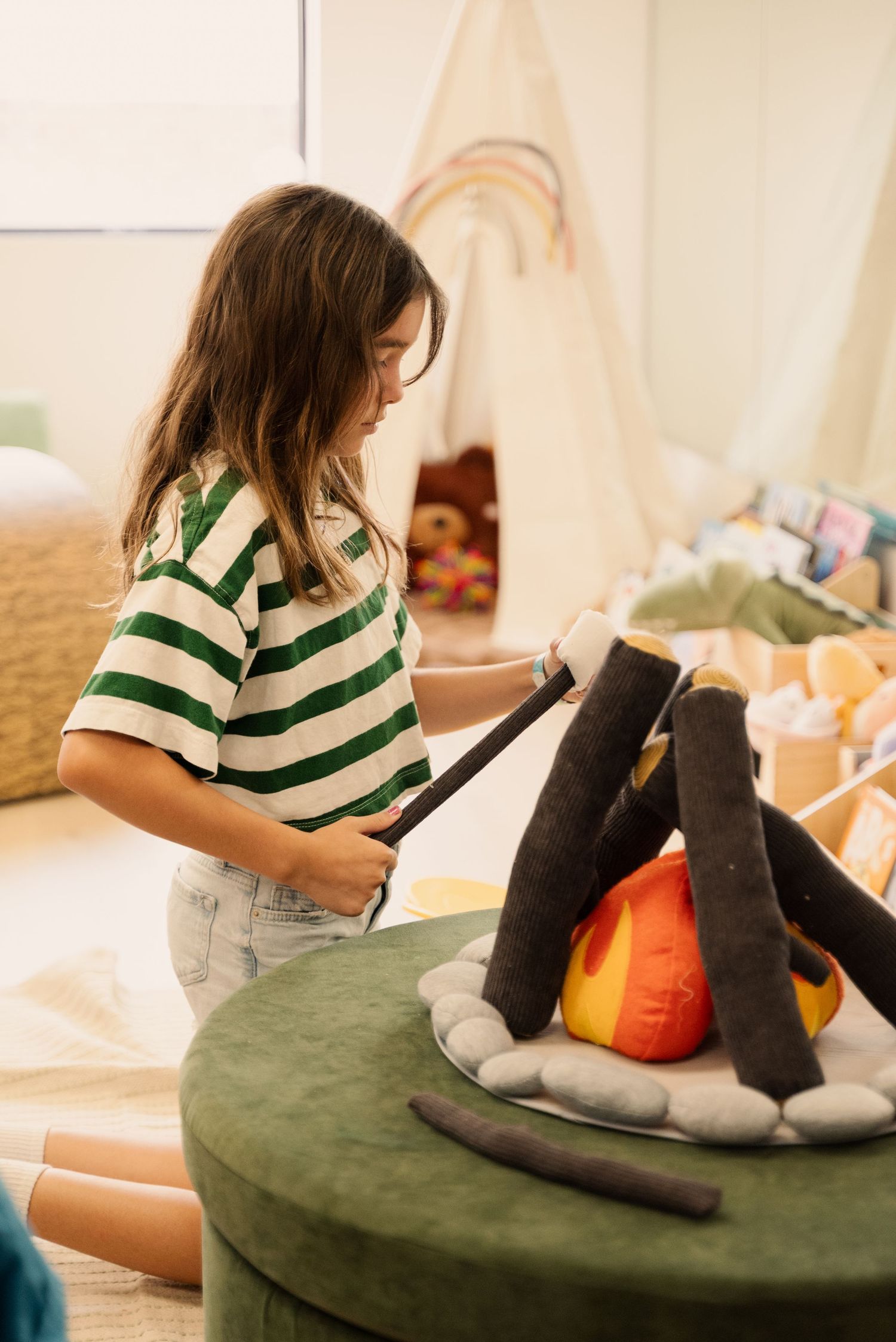 Person in striped shirt arranging items on a round green cushion.