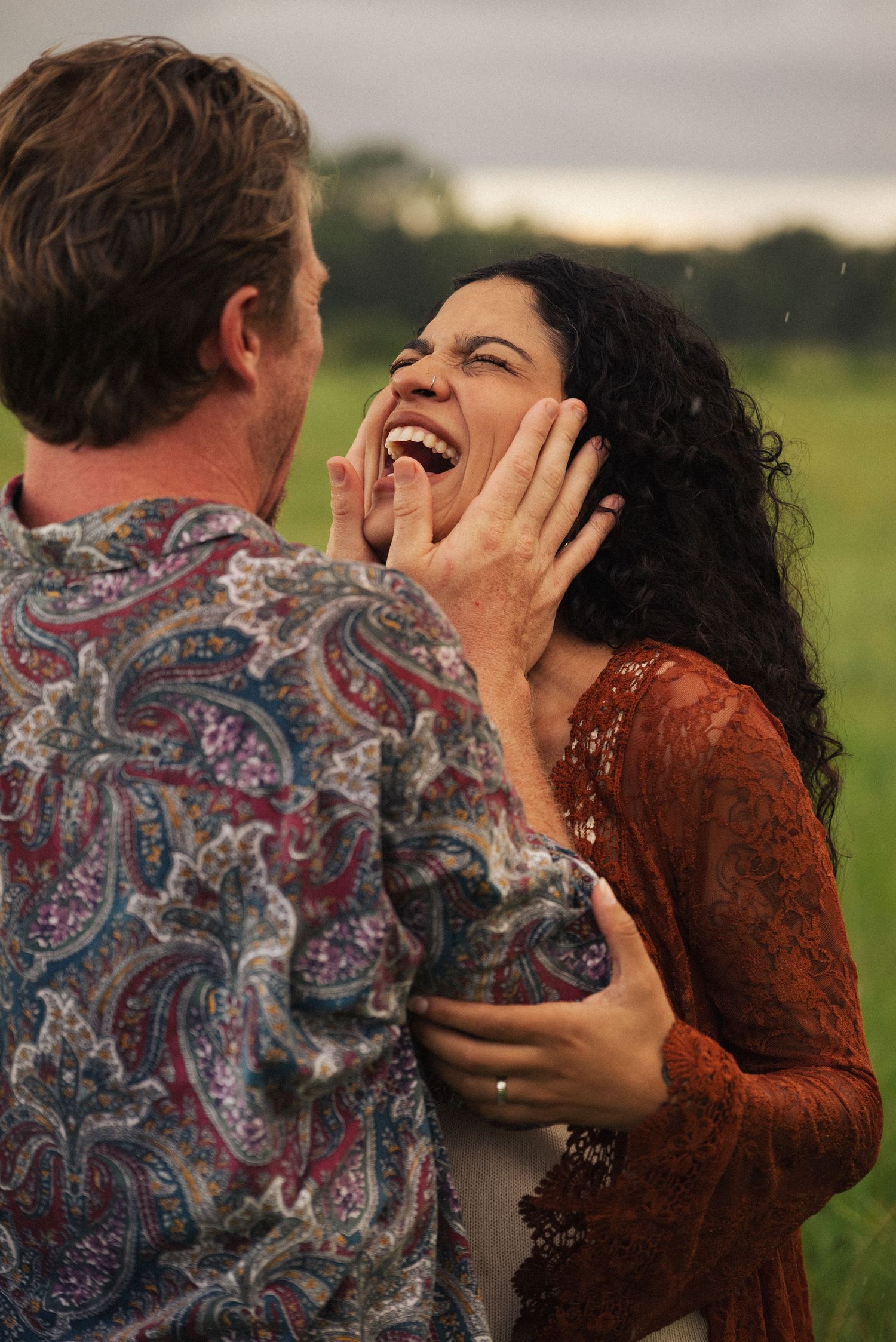 Couple sharing a joyful moment together in a field at sunset.