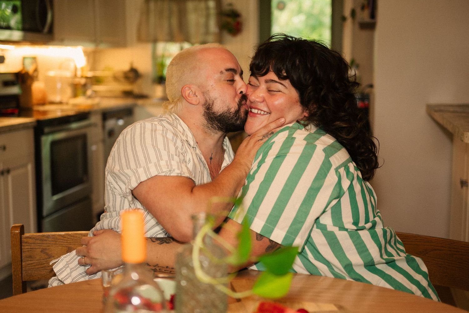 Intimate kitchen moment captured under warm lighting with fruit on table.
