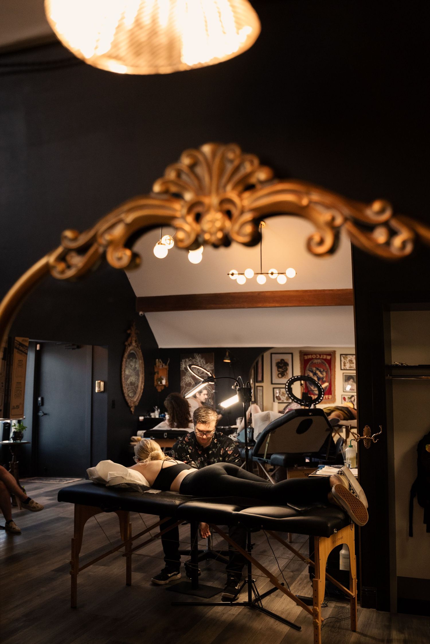 Dimly lit tattoo studio interior with massage tables and decorative lighting creating a moody atmosphere.